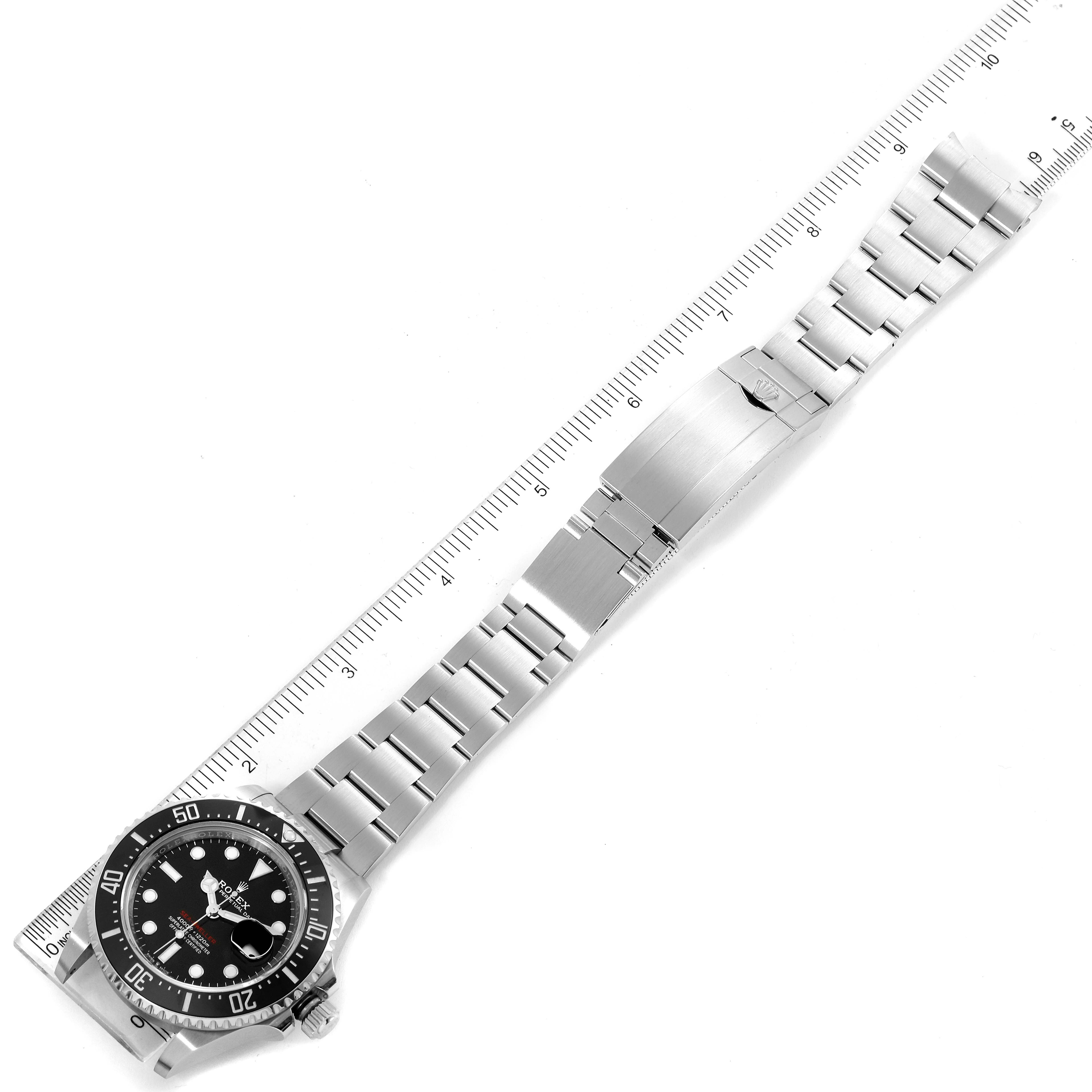 The image shows a top-down view of the Rolex Sea-Dweller 126600 Men
s Stainless Steel Black Dial 126600 Men
s Stainless Steel Black Dial watch and its bracelet, displayed alongside a ruler.
