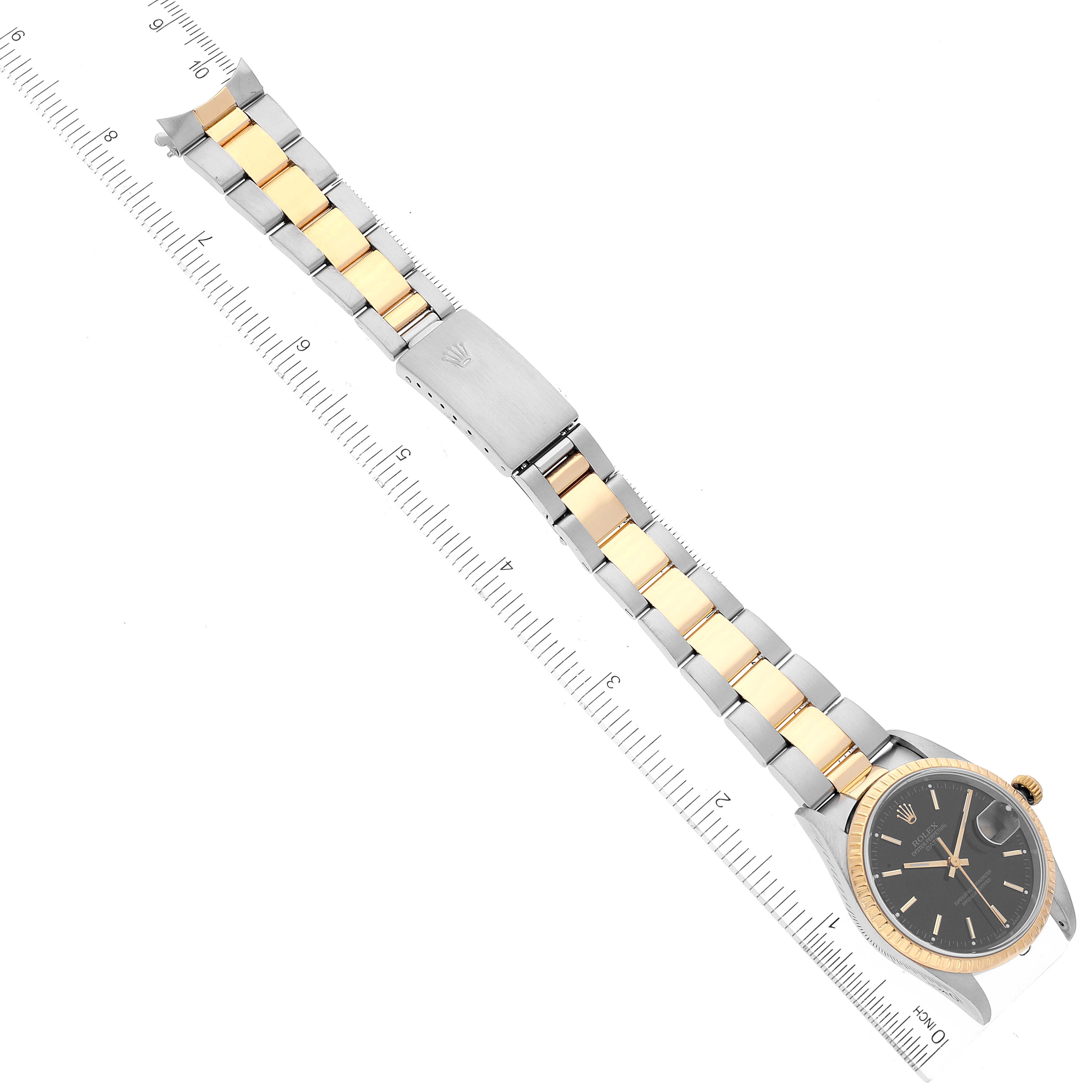This image shows a Rolex Date 15223 Men's Steel and Gold (two tone) Black Dial 15223 Men's Steel and Gold (two tone) Black Dial watch from a top-down angle, displaying the face, bezel, and band with a ruler for scale.