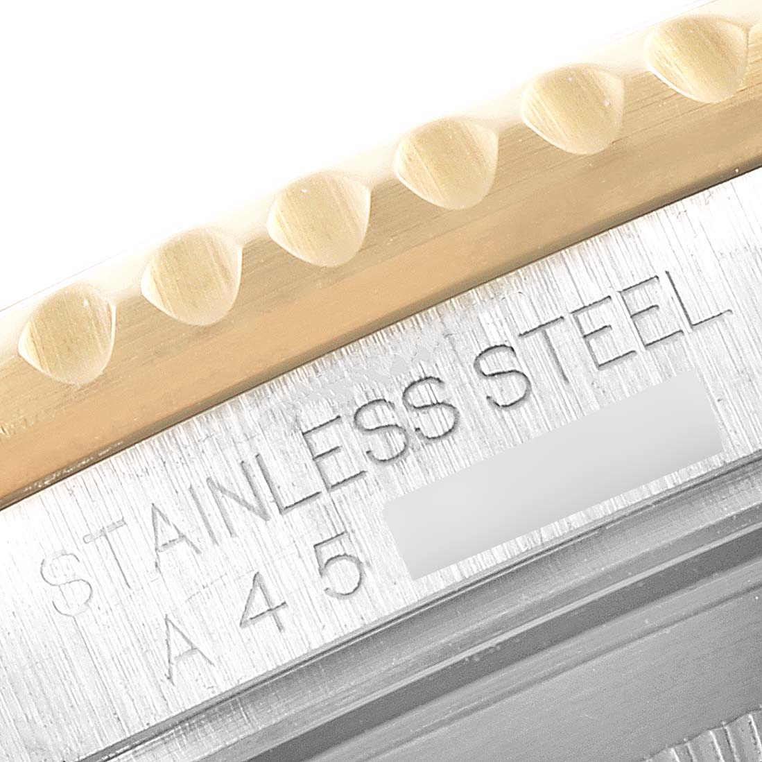 This image shows a close-up of the edge of the bezel and case back of a Rolex Submariner 16613 Men's Steel and Gold (two tone) Black Dial 16613 Men's Steel and Gold (two tone) Black Dial, highlighting the "STAINLESS STEEL" engraving.