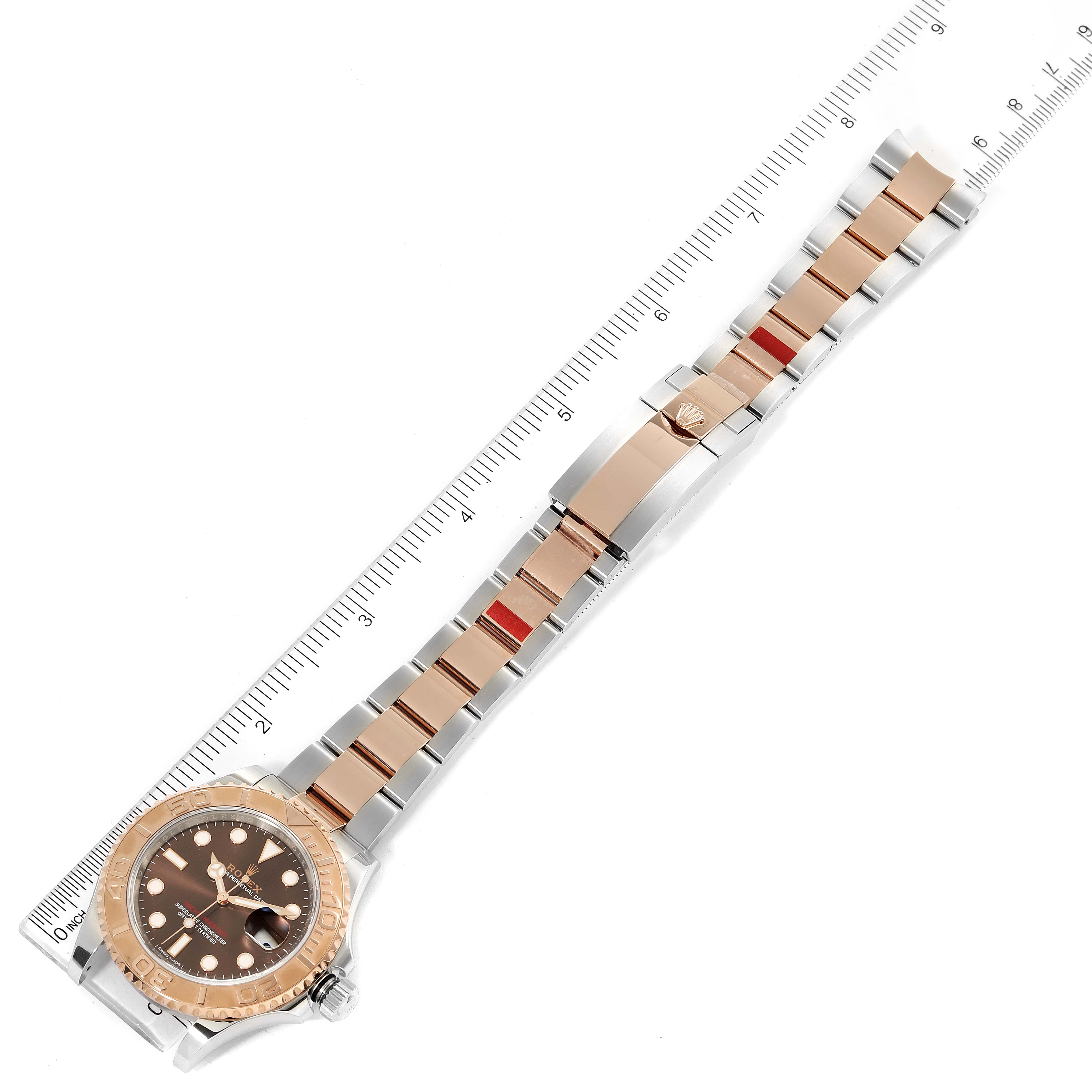 This image shows the full length of a Rolex Yacht-Master 116621 Men's Steel and Gold (two tone) Brown Dial 116621 Men's Steel and Gold (two tone) Brown Dial watch laid flat next to a ruler, highlighting the watch face, bracelet, and clasp.