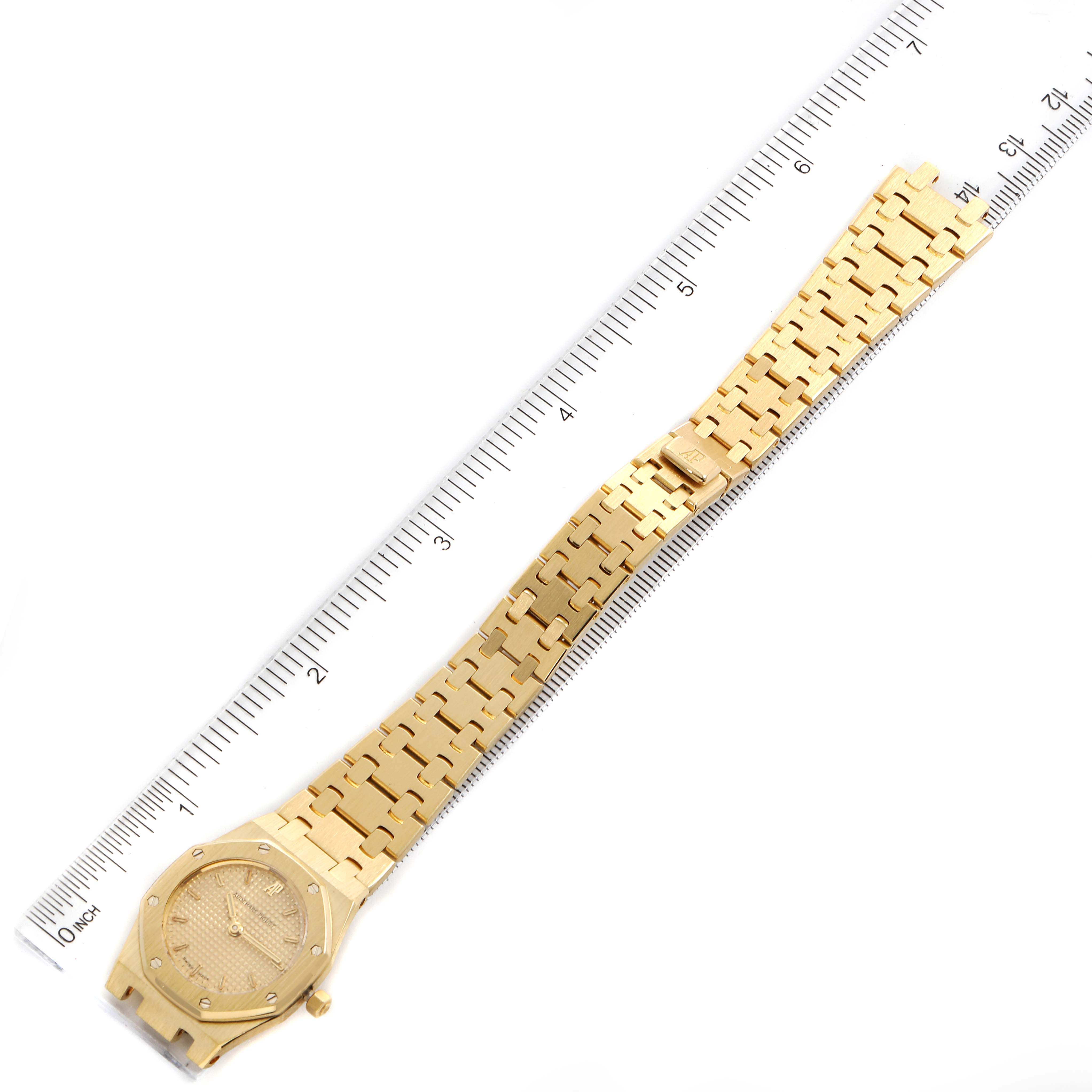 The image shows a full view of the Audemars Piguet Royal Oak D6519 Women's Yellow Gold Champagne Dial D6519 Women's Yellow Gold Champagne Dial watch, including the watch face and bracelet, alongside a ruler for scale.
