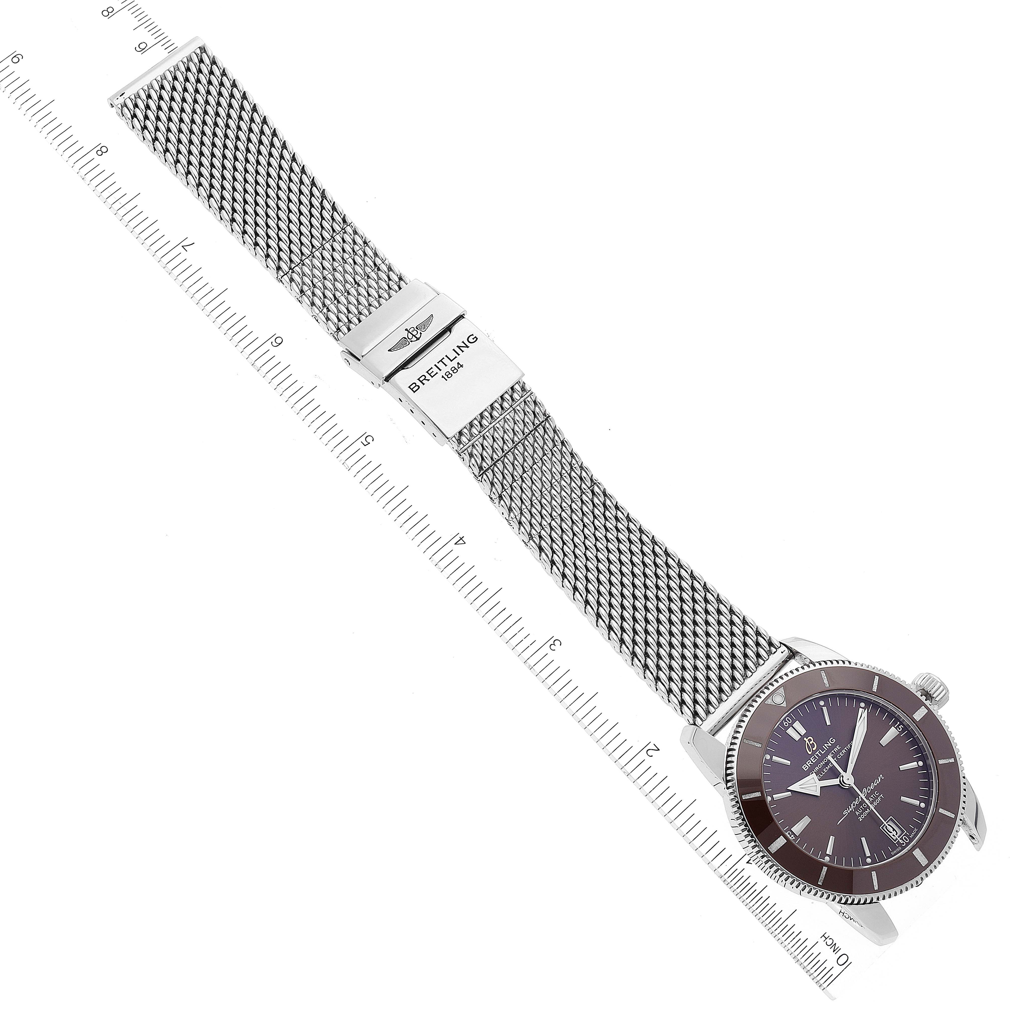 The image shows a top-down view of a Breitling Superocean AB2010 Men's Stainless Steel Brown Dial AB2010 Men's Stainless Steel Brown Dial watch with a metal mesh bracelet and clasp, alongside a ruler for scale.