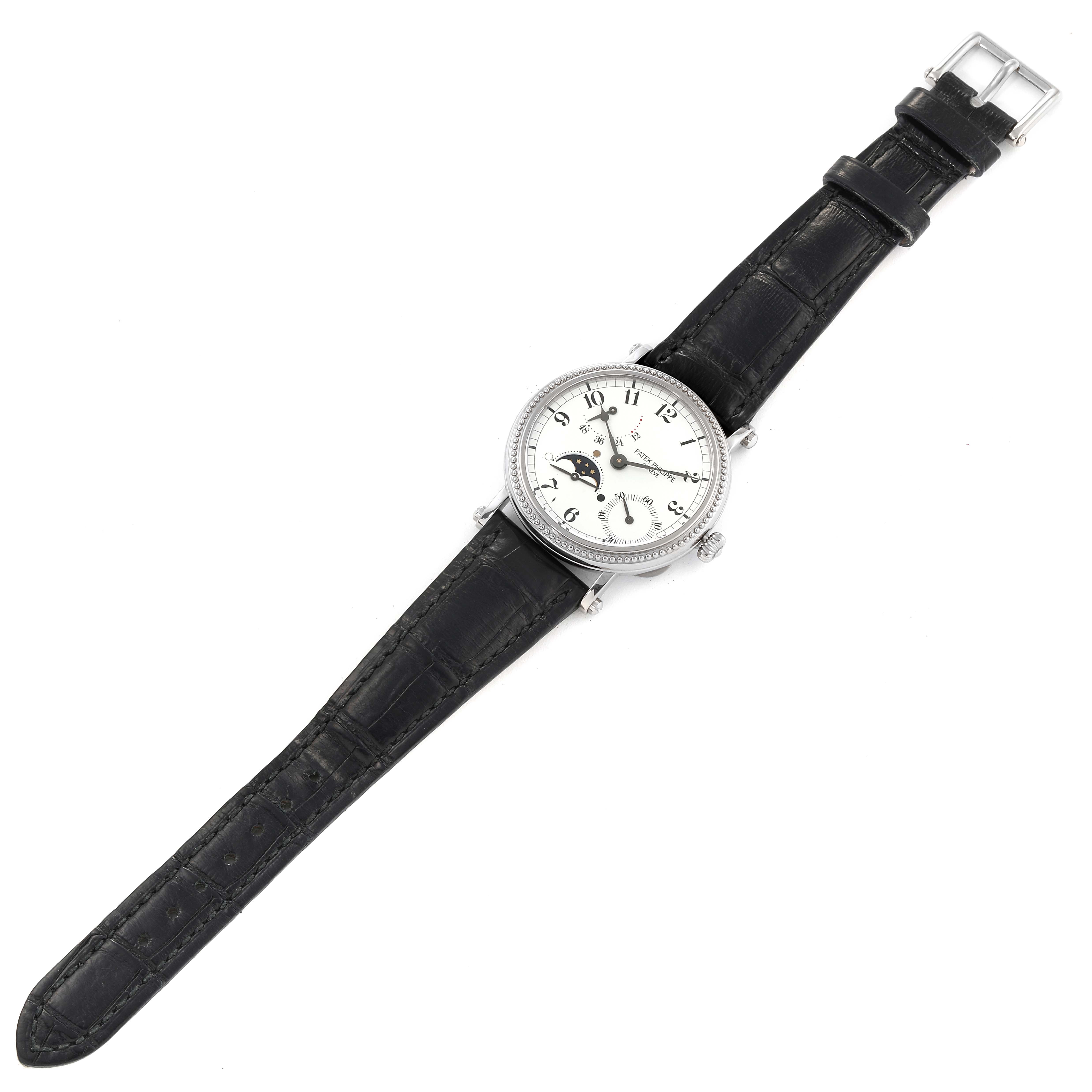 The image shows a Patek Philippe Complications 5015G-001 Men's White Gold White Dial 5015G-001 Men's White Gold White Dial model watch from an overhead angle, highlighting its face, black leather strap, and buckle.