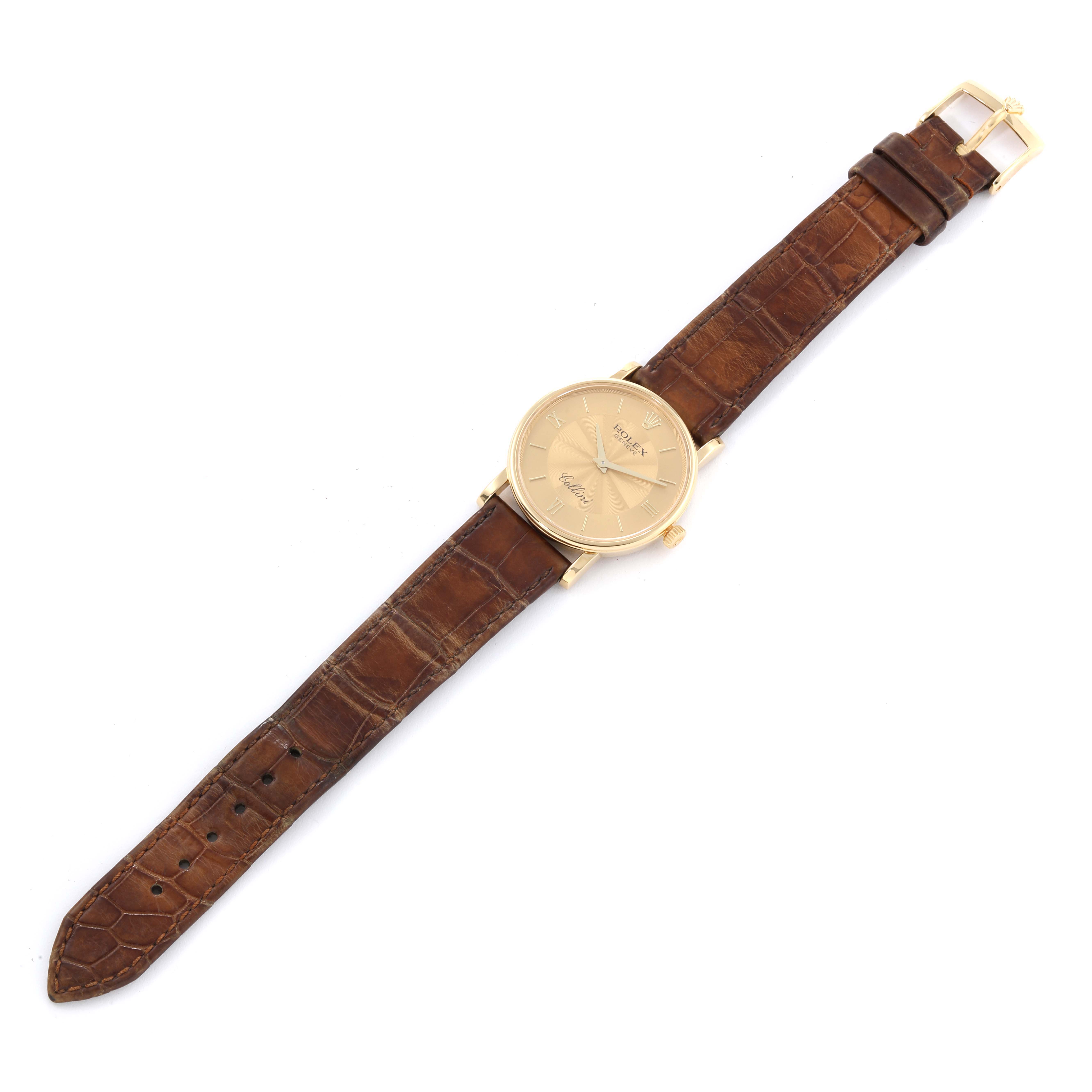 The Rolex Cellini 5115 Men's Yellow Gold Champagne Dial 5115 Men's Yellow Gold Champagne Dial watch is shown from a top-down angle, displaying its gold watch face, crown, and brown leather strap in full length.