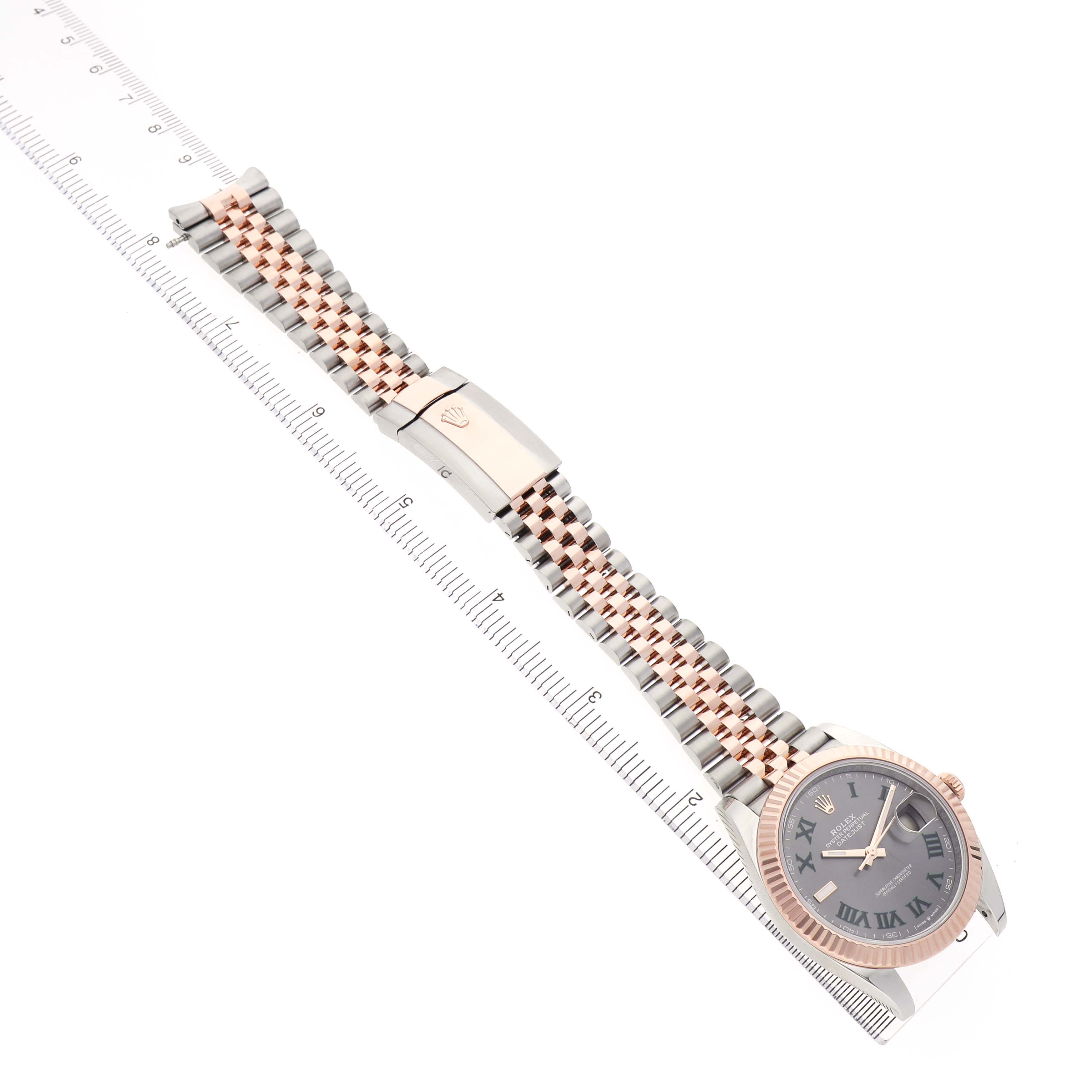 The Rolex Datejust 41 126331 Men's Stainless Steel Grey Dial watch is shown at an angle highlighting the band, clasp, and partially the face, alongside a ruler.