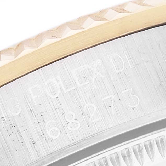 The image shows a close-up of the bezel and part of the side of the Rolex Mid-Size 68273 Women's Steel and Gold (two tone) Champagne Dial 68273 Women's Steel and Gold (two tone) Champagne Dial model watch, with engraved text partially visible.