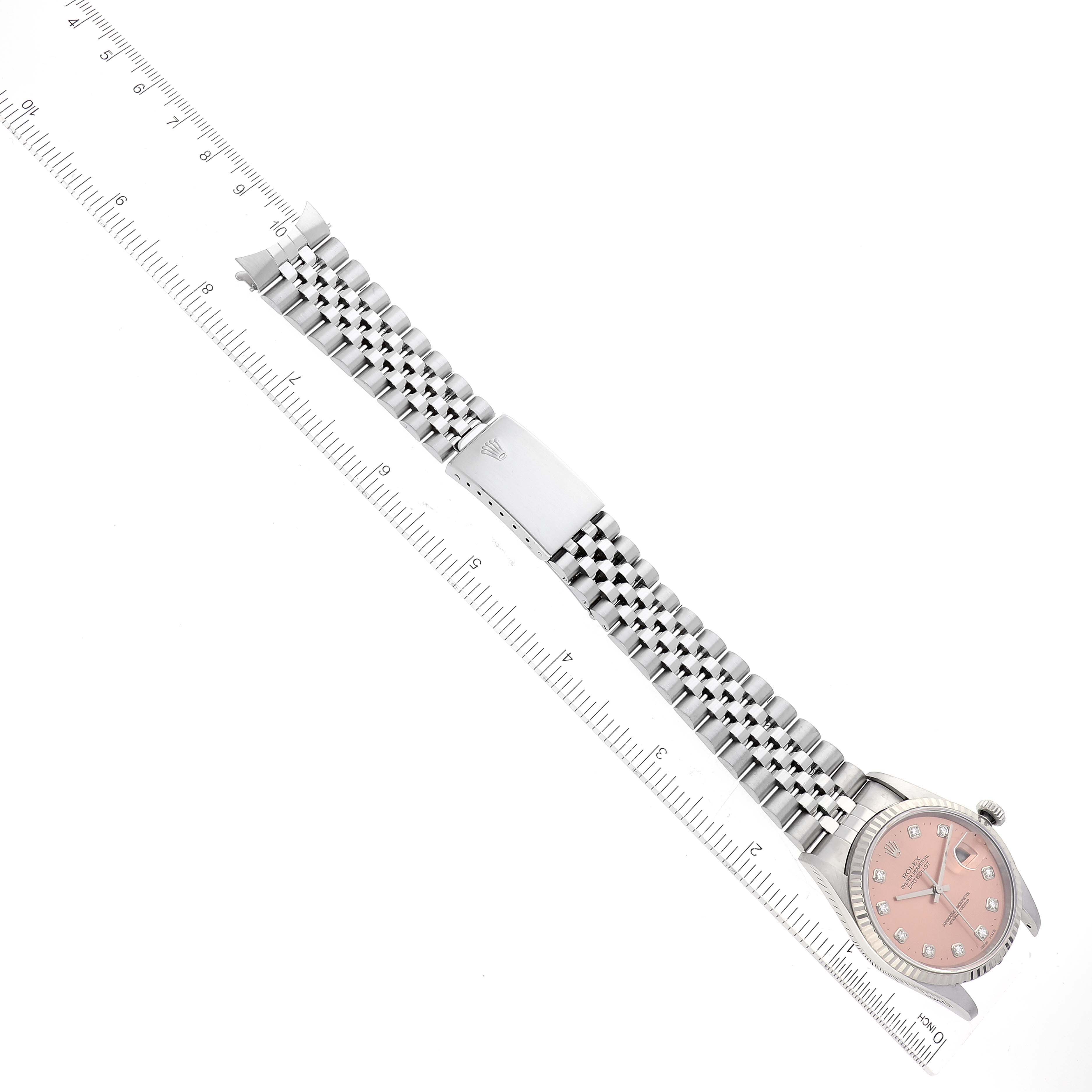 The image shows the Rolex Datejust 16234 Men's Stainless Steel Pink Dial 16234 Men's Stainless Steel Pink Dial watch model laid flat, displaying its face, bezel, bracelet, and clasp, alongside a ruler.