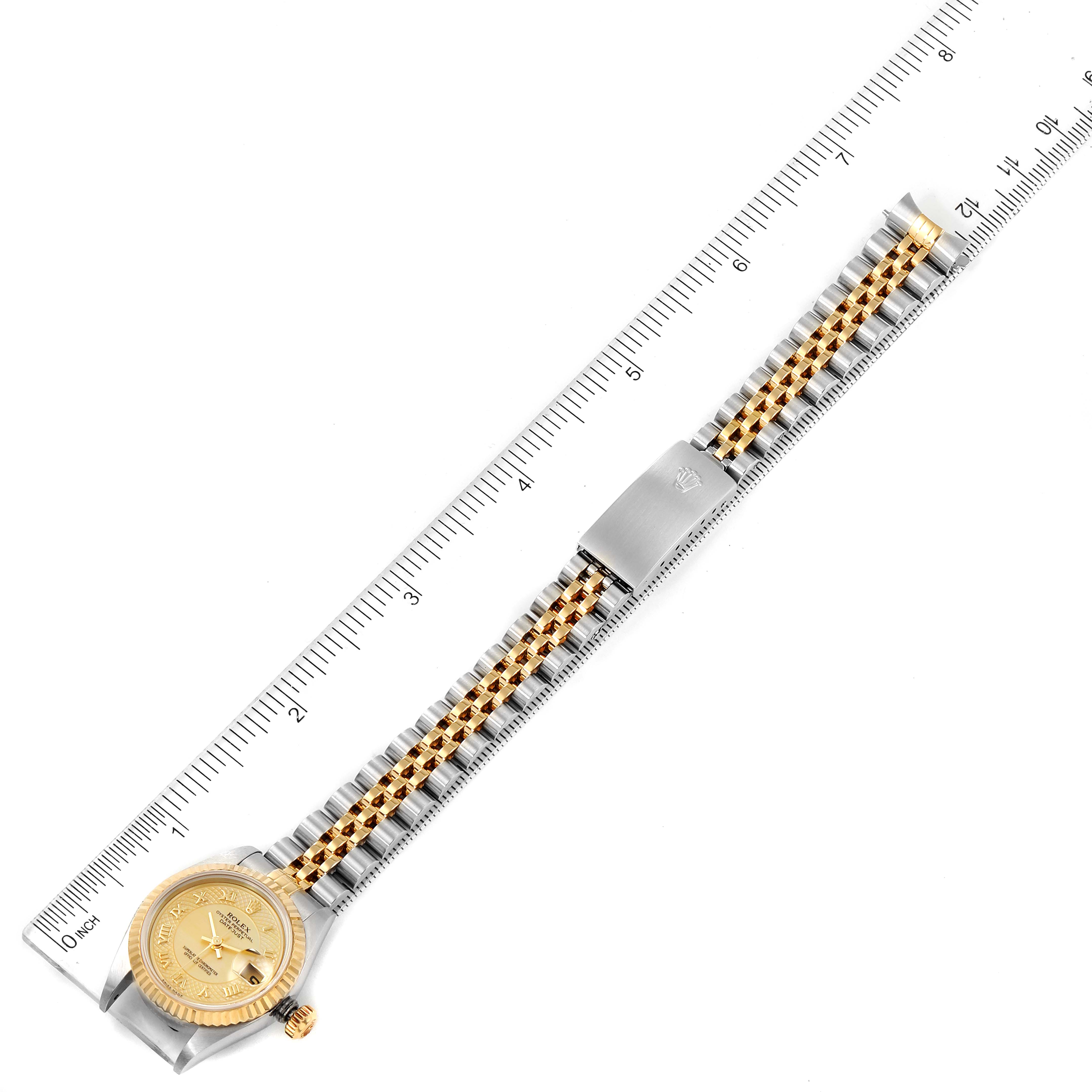 This image shows a Rolex Datejust 79173 Women
s Steel and Gold (two tone) Mother of Pearl Dial 79173 Women
s Steel and Gold (two tone) Mother of Pearl Dial watch laid flat next to a ruler, capturing the entire watch including the face and band.