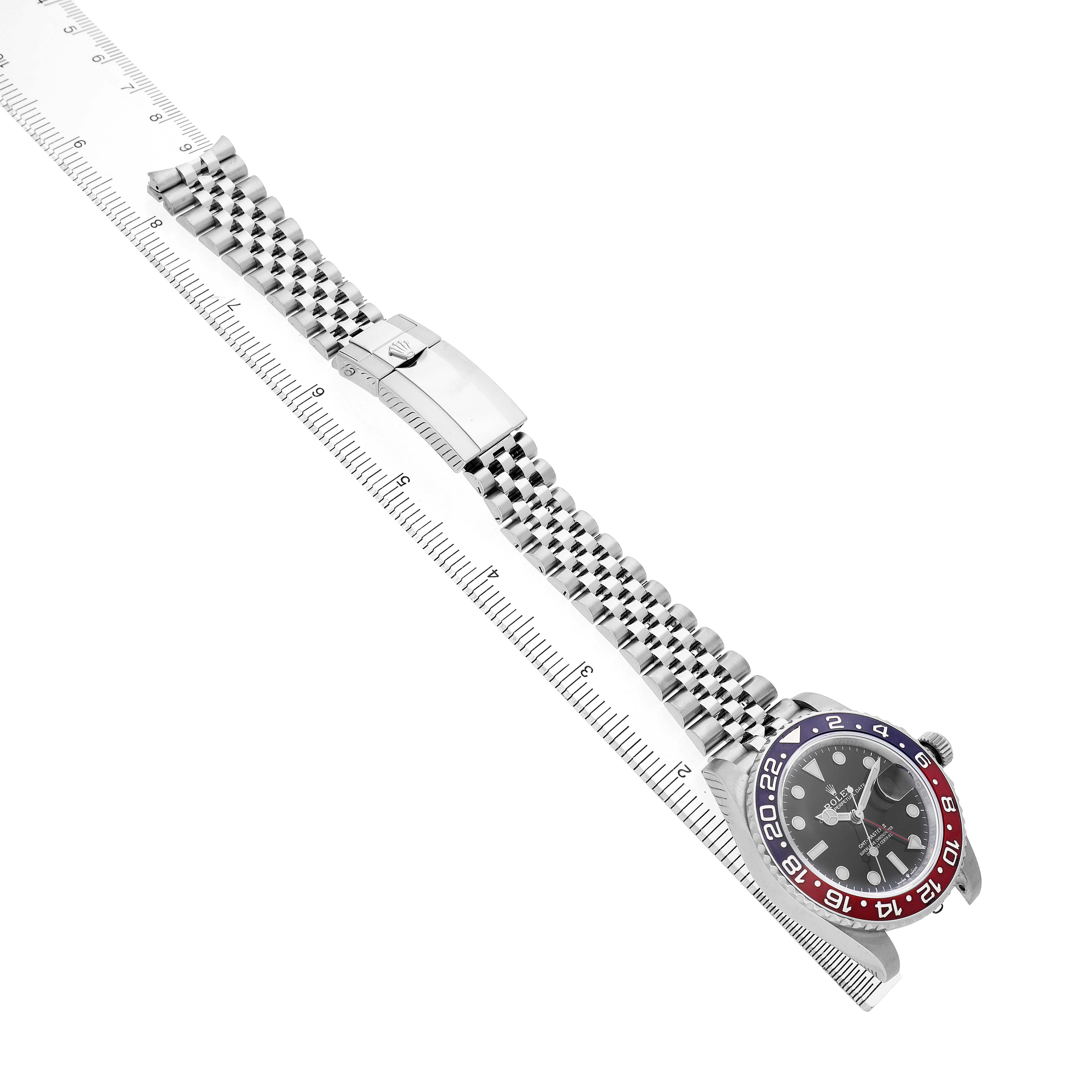The Rolex GMT-Master 126710BLRO Men's Stainless Steel Black Dial watch is shown at an angle with focus on the strap, bezel, and dial alongside a ruler for scale.