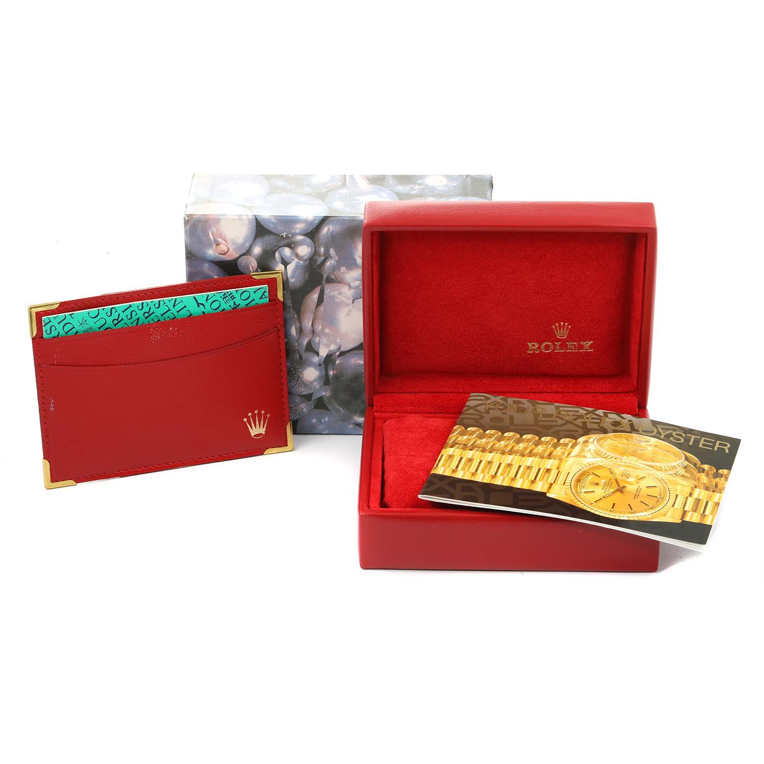 The image shows the packaging and accessories for a Rolex President 69178 Women
s Yellow Gold Champagne Dial 69178 Women
s Yellow Gold Champagne Dial model, including a red watch box, a booklet, and a card holder.