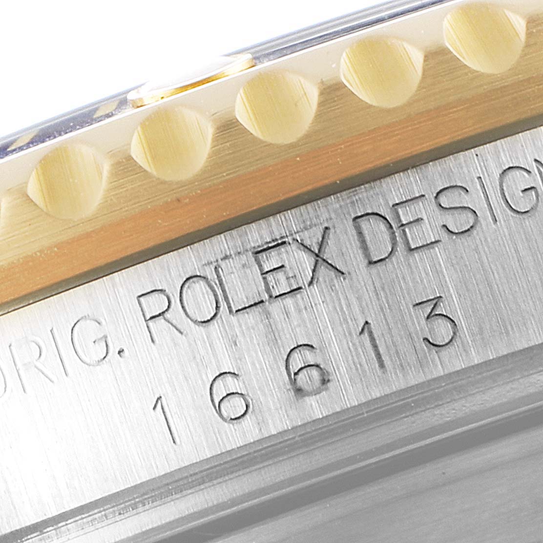 This close-up image shows the edge of the bezel and the model number engraving on the side of a Rolex Submariner 16613 Men's Steel and Gold (two tone) Blue Dial 16613 Men's Steel and Gold (two tone) Blue Dial watch.