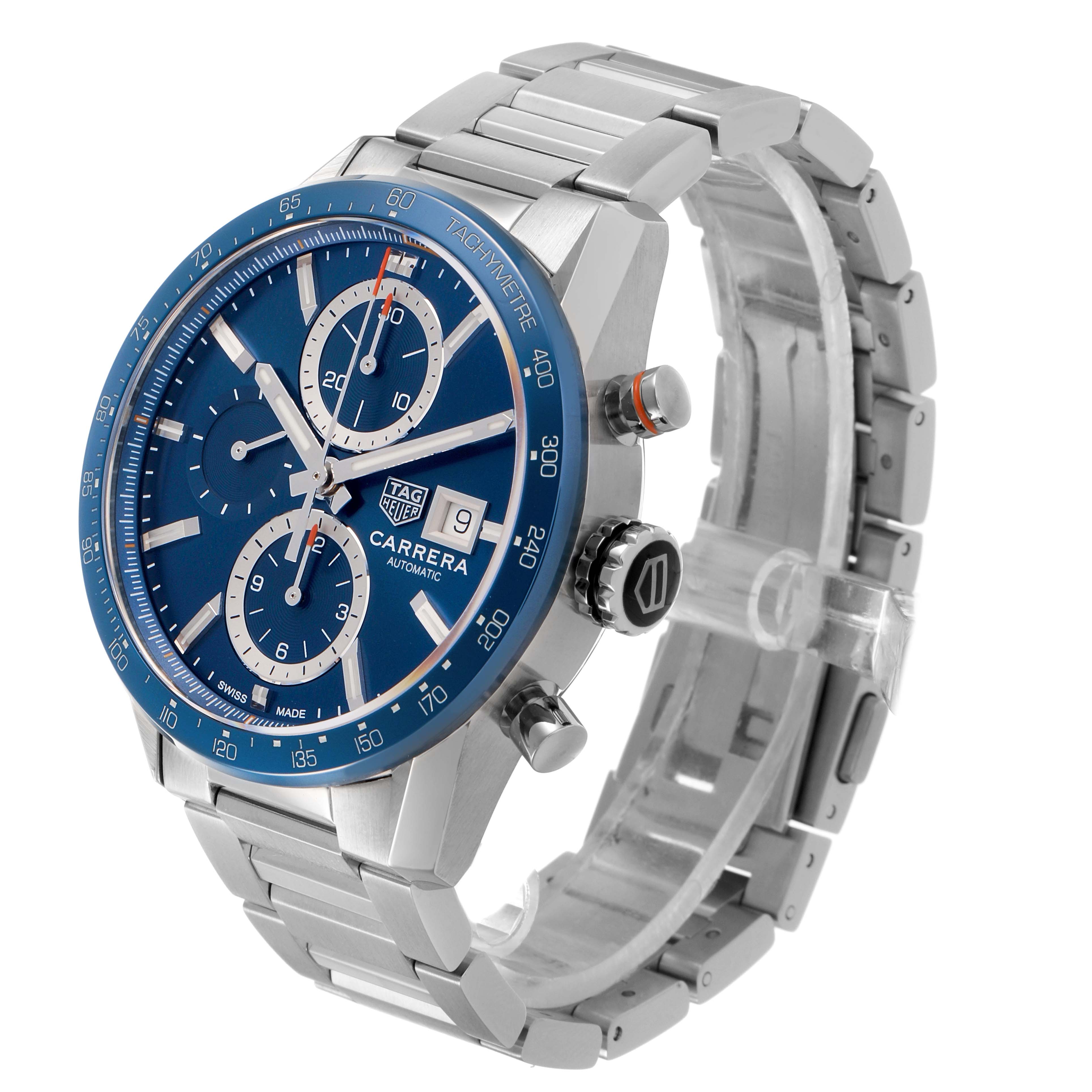 The image shows a TAG Heuer Carrera watch at a three-quarter angle, highlighting the blue dial, tachymeter bezel, and metal bracelet.