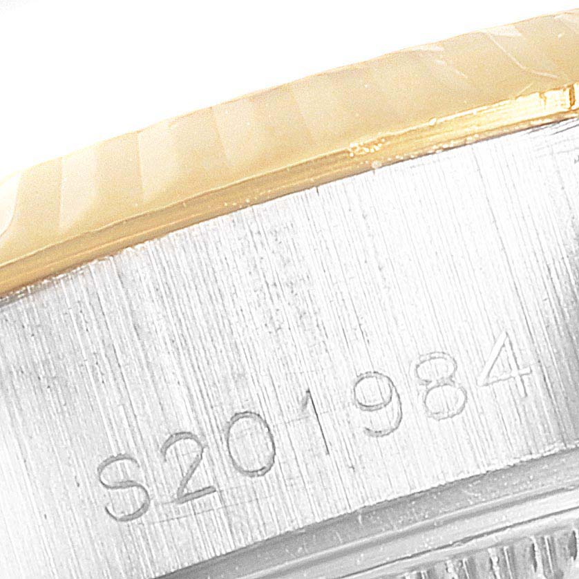 The image shows the side view of a Rolex Datejust 69173 Women
s Steel and Gold (two tone) Champagne Dial 69173 Women
s Steel and Gold (two tone) Champagne Dial watch featuring part of the bezel and the serial number engraving.