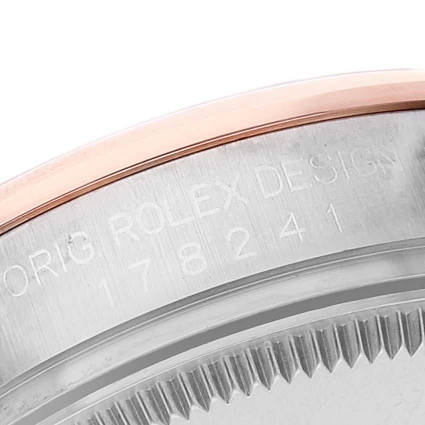 This close-up image shows the side of a Mid-Size Rolex watch, featuring the engraved serial number and part of the bezel.