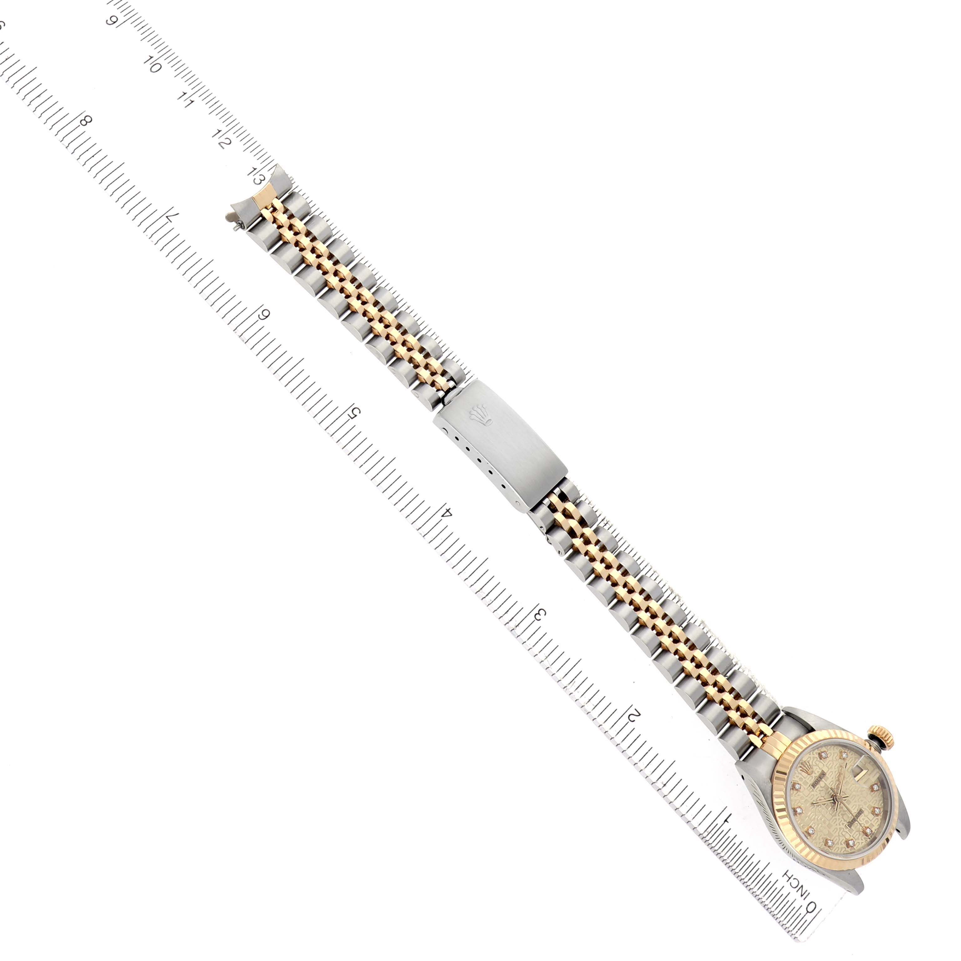 The image shows a Rolex Datejust 69173 Women
s Steel and Gold (two tone) Champagne Dial 69173 Women
s Steel and Gold (two tone) Champagne Dial watch at a diagonal angle, displaying the face, bracelet, and clasp beside a measuring ruler.