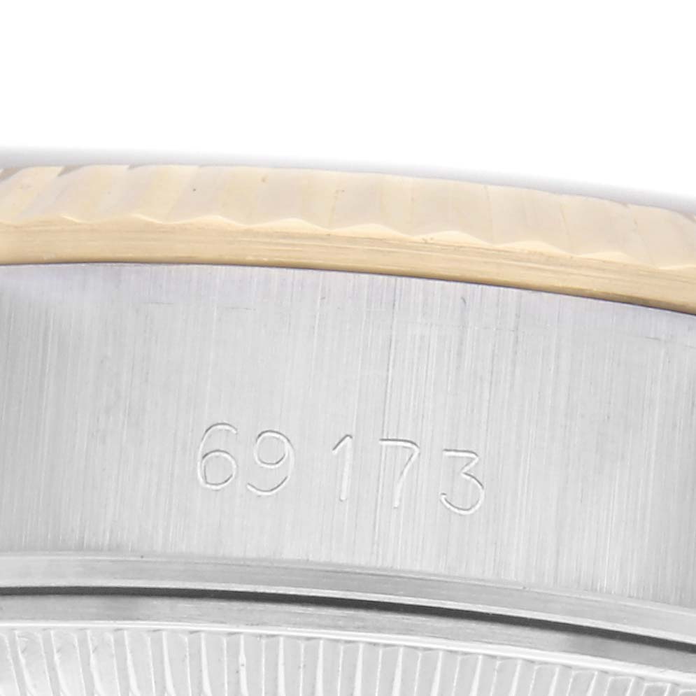 The image shows the side of a Rolex Datejust 69173 Women
s Steel and Gold (two tone) Silver Dial 69173 Women
s Steel and Gold (two tone) Silver Dial case, displaying the engraved model number and a partial view of the bezel.