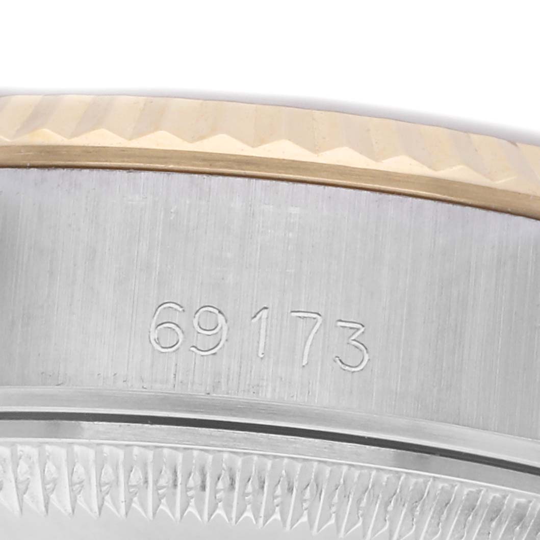 The image shows a close-up of the side of a Rolex Datejust 69173 Women
s Steel and Gold (two tone) Champagne Dial 69173 Women
s Steel and Gold (two tone) Champagne Dial watch, highlighting the bezel and case with engraved numerals.