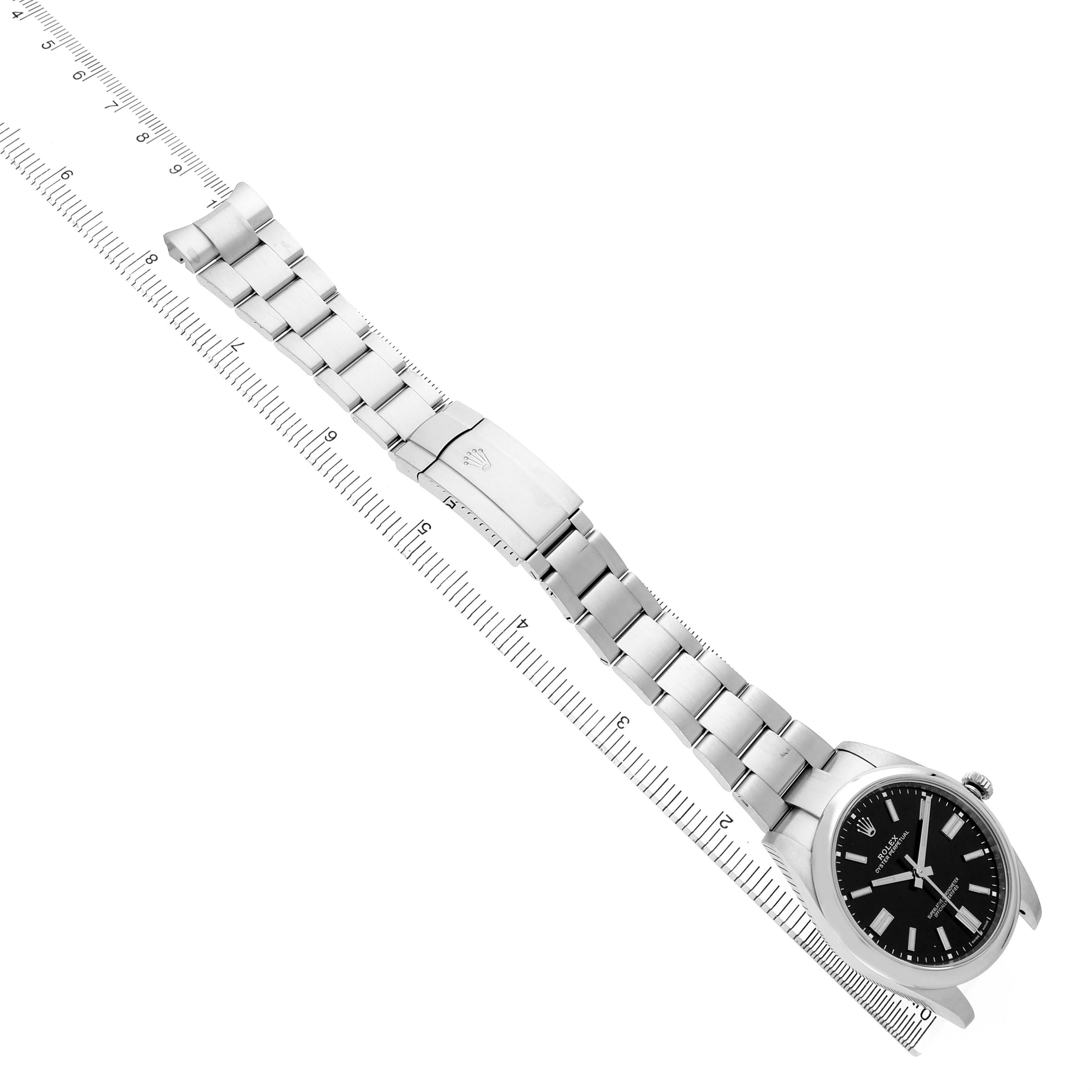 The Rolex Oyster Perpetual M124300-0002 Men's Stainless Steel Black Dial watch is shown from an angled side view, displaying the full bracelet and clasp alongside a ruler.