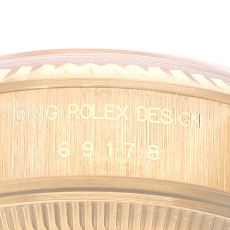 The image shows a close-up angle of the side of a Rolex President 69178 Women
s Yellow Gold Champagne Dial 69178 Women
s Yellow Gold Champagne Dial watch case, displaying the engraving "ORIG ROLEX DESIGN 69178."