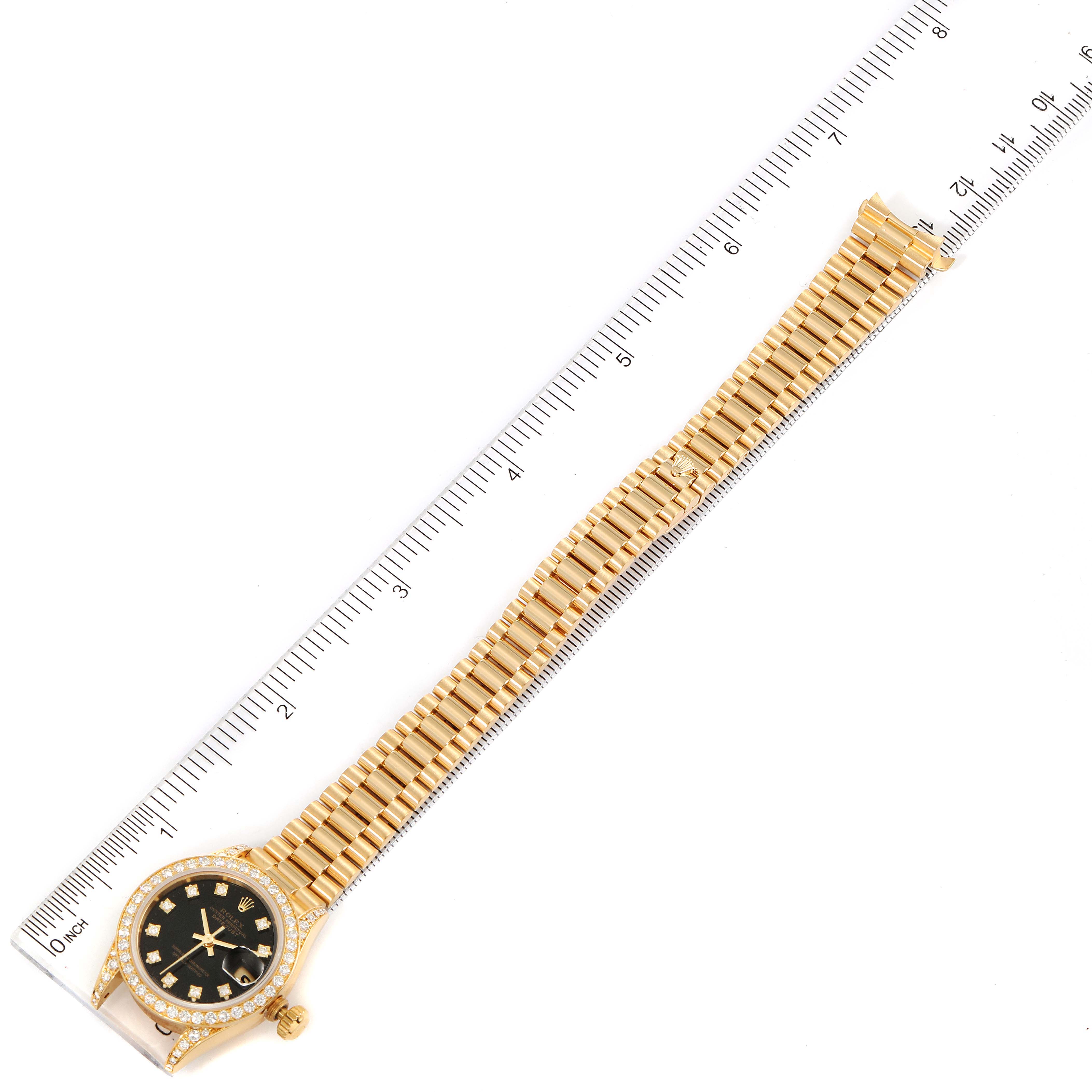 The image shows a Rolex President 69158 Women's Yellow Gold Black Dial 69158 Women's Yellow Gold Black Dial model watch laid flat with the dial, case, and full bracelet visible against a ruler for scale.