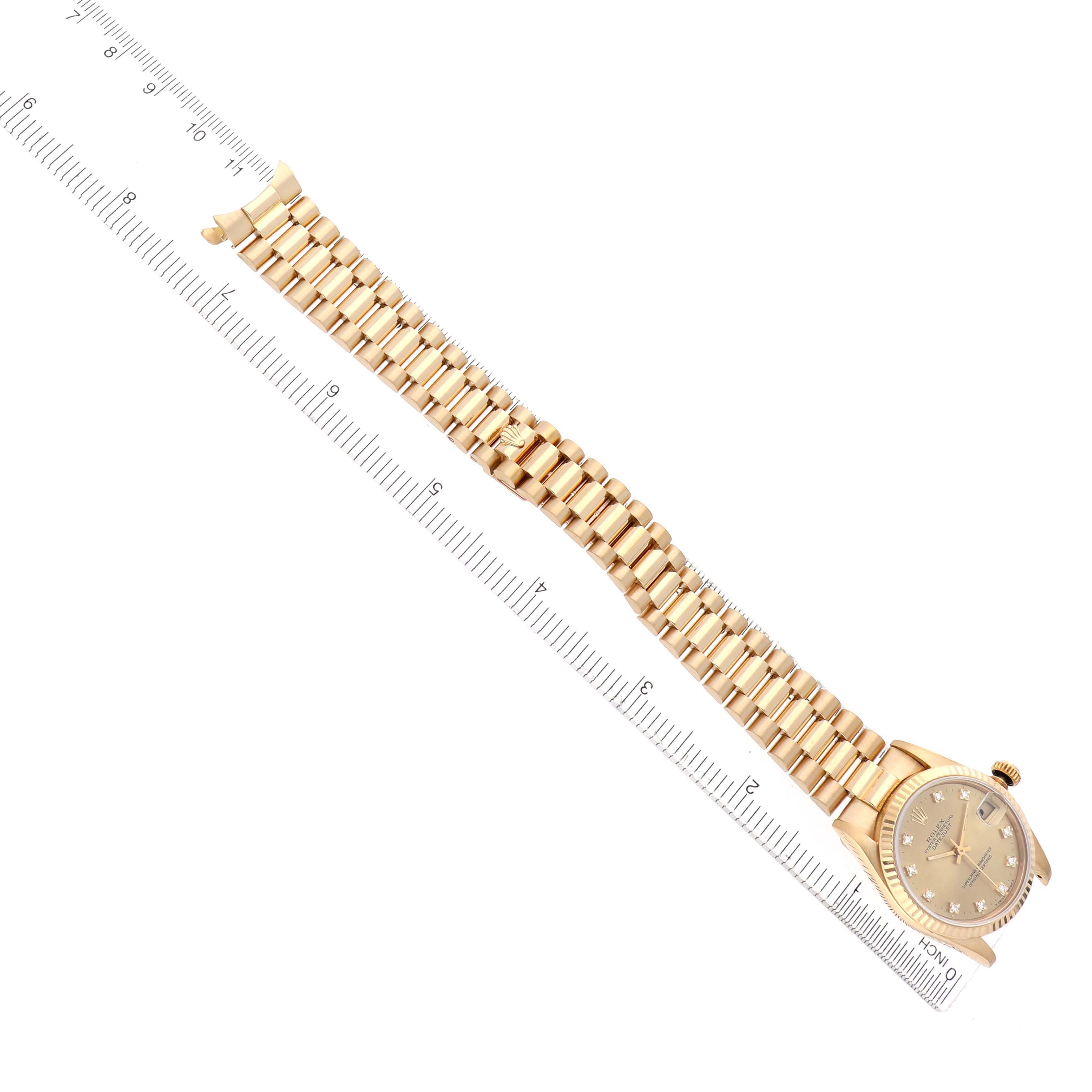 The Rolex President 68278 Women's Yellow Gold Champagne Dial 68278 Women's Yellow Gold Champagne Dial model watch is shown at a top-down angle, featuring the bracelet and face near a ruler for scale.