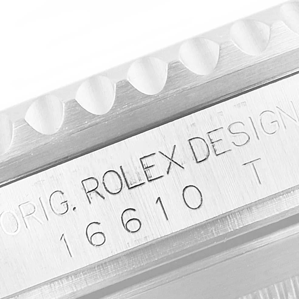 The image shows a close-up of the engraved case side of a Rolex Submariner 16610 Men
s Stainless Steel Black Dial 16610 Men
s Stainless Steel Black Dial model 16610, including parts of the bezel.