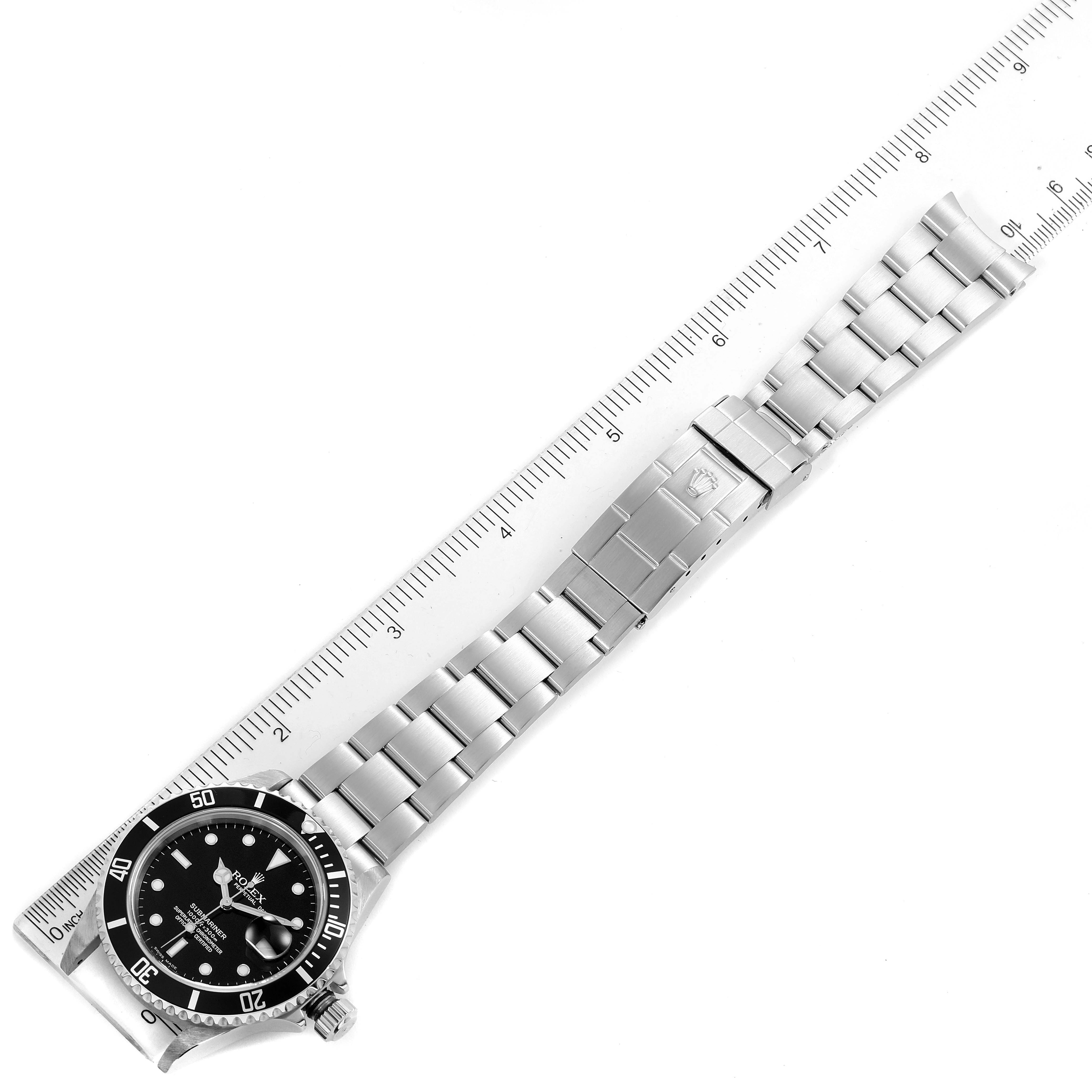 The image shows a full frontal view of the Rolex Submariner 16610 Men
s Stainless Steel Black Dial 16610 Men
s Stainless Steel Black Dial watch, including its bezel, dial, and bracelet, alongside a ruler for scale.