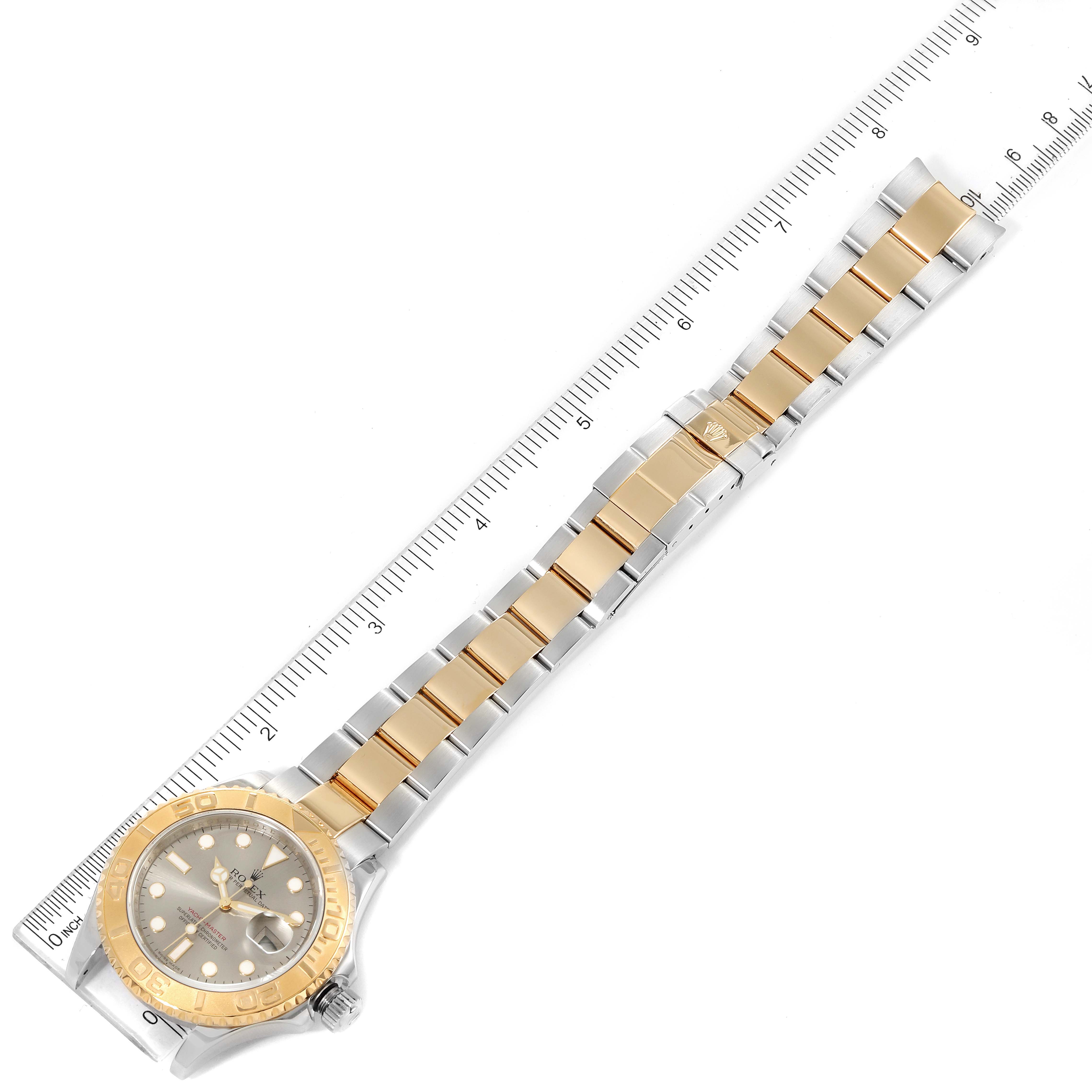 This Rolex Yacht-Master 16623 Men
s Steel and Gold (two tone) Grey Dial 16623 Men
s Steel and Gold (two tone) Grey Dial watch is shown from a top-down angle, highlighting the face, gold bezel, and bi-metallic bracelet beside a ruler for scale.
