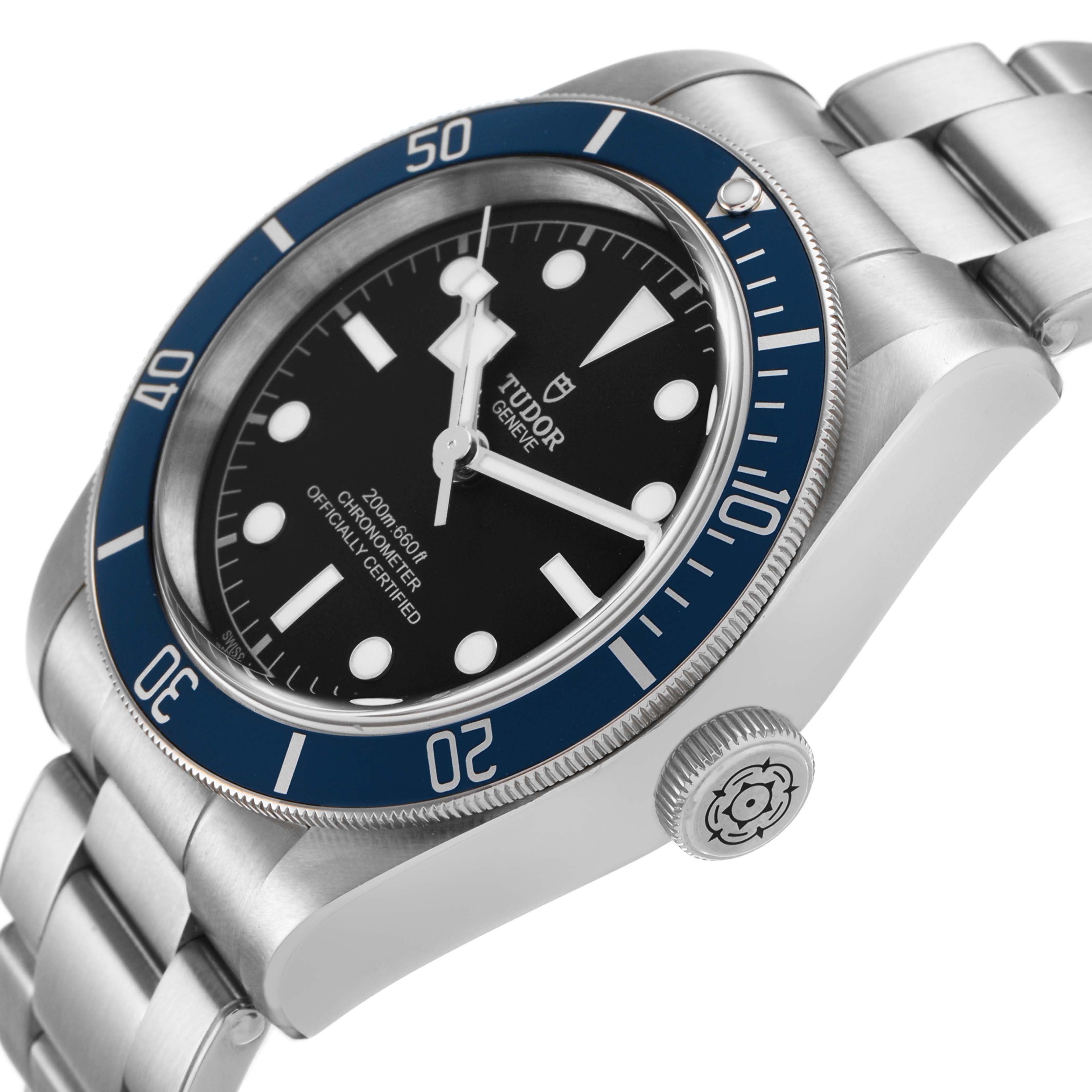 The Tudor Heritage Black Bay 79230B Men's Stainless Steel Black Dial watch is shown from an angled view, highlighting the bezel, dial, crown, and bracelet.