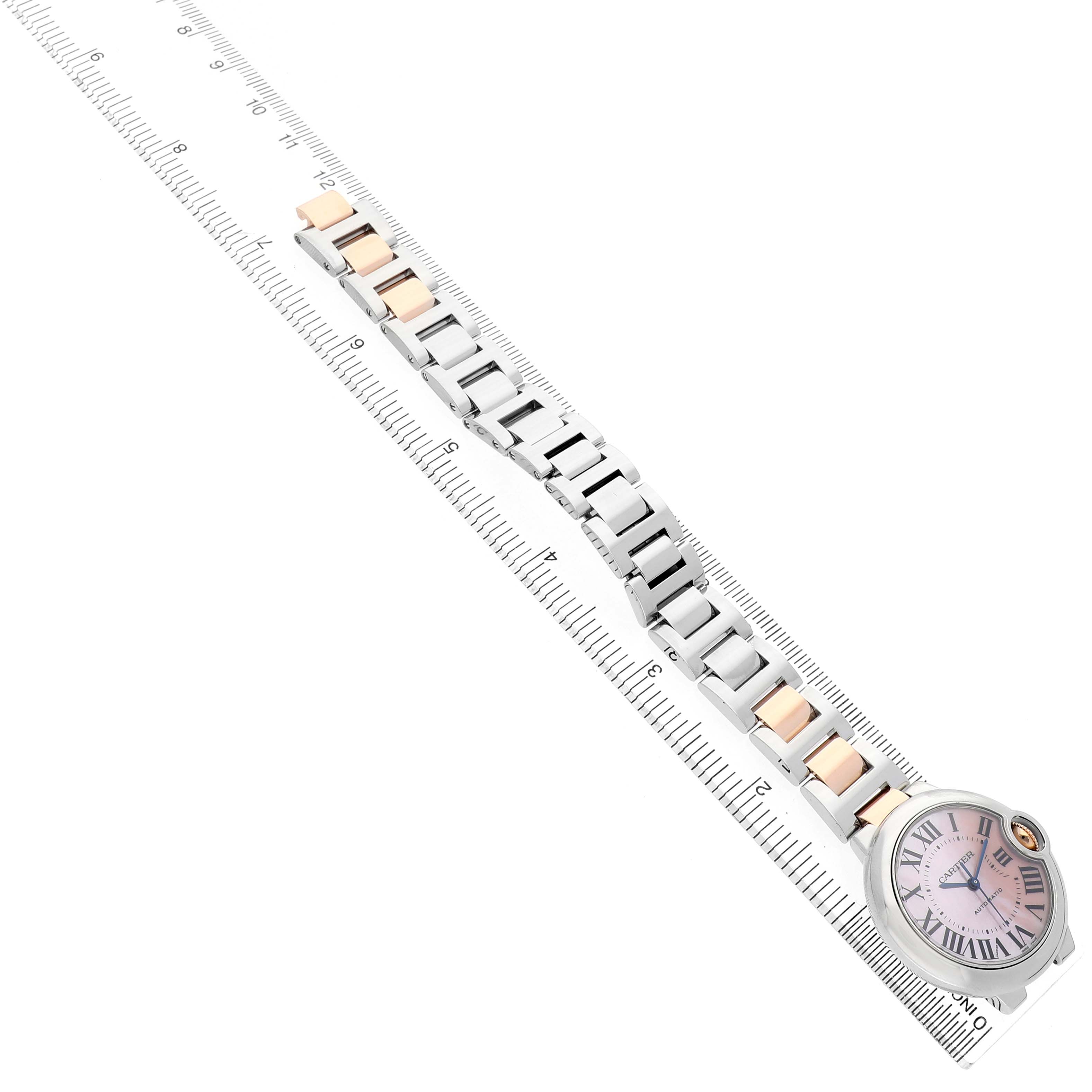 The image shows a Ballon Bleu by Cartier from a top-down angle, highlighting its bracelet and face alongside a ruler for scale.