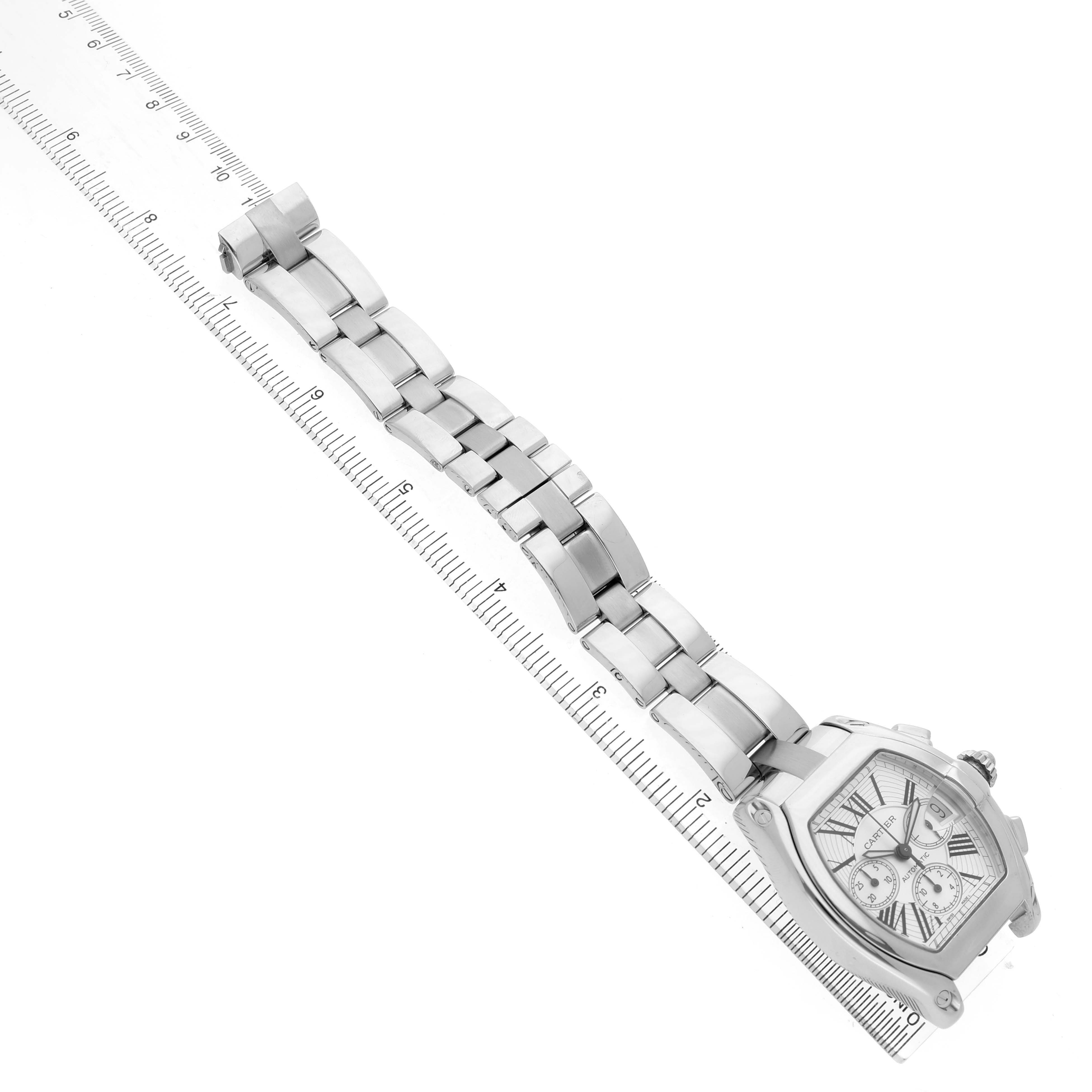The Cartier Roadster W62019X6 Men's Stainless Steel Silver Dial watch is shown at an angle displaying its bracelet and case diagonally along a ruler.