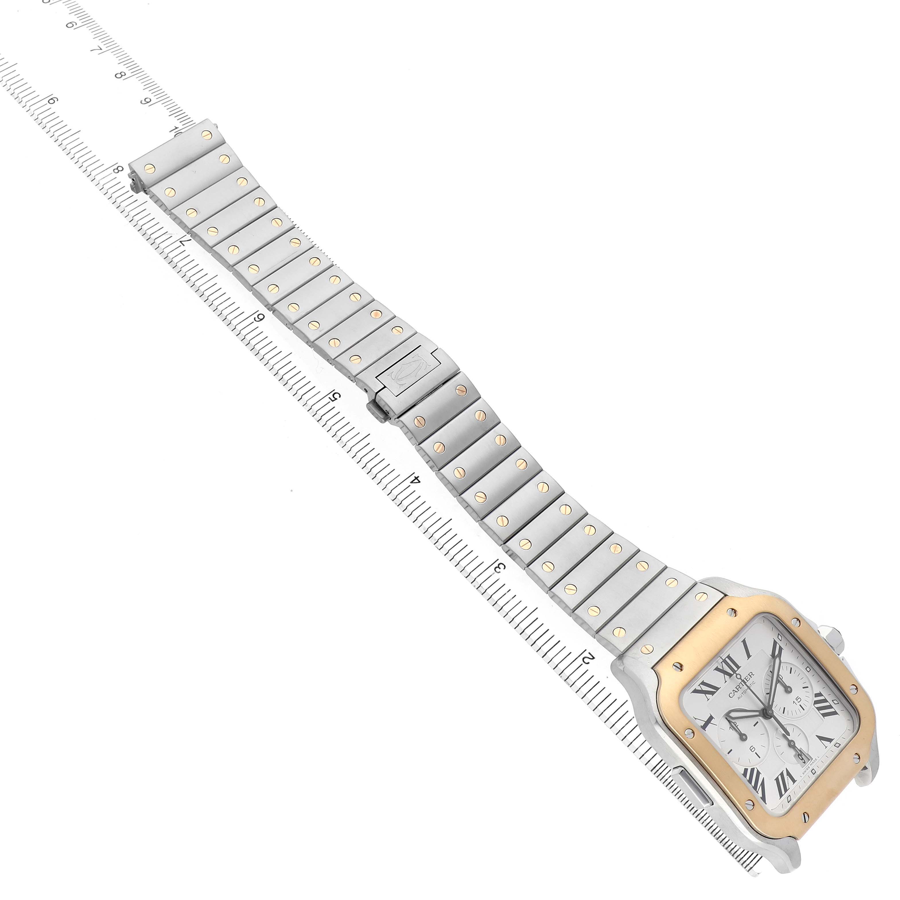 The Cartier Santos W2SA0008 Men's Stainless Steel Silver Dial watch is shown at an angled view with the face, bezel, and metal bracelet visible alongside a ruler for scale.