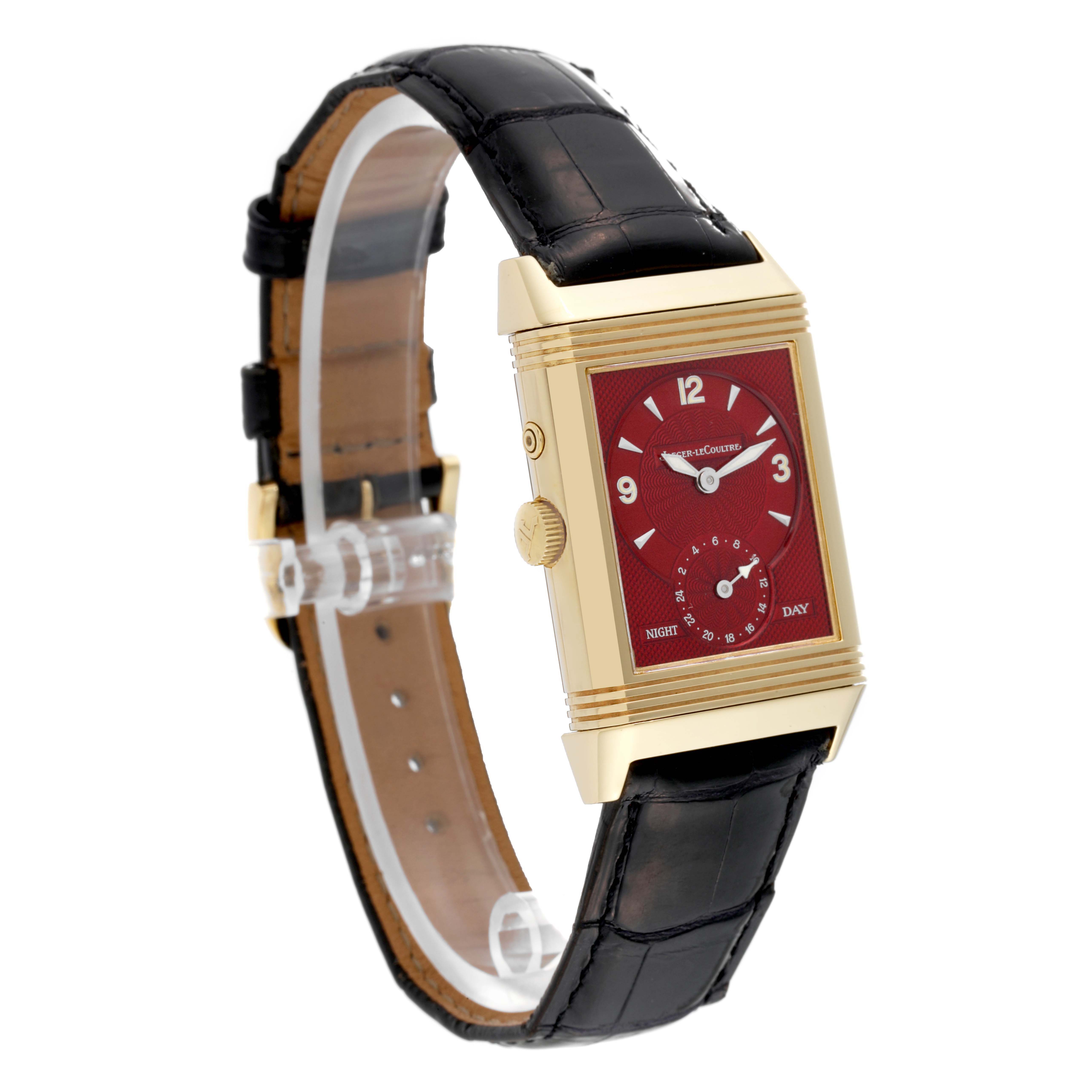 The Jaeger-LeCoultre Reverso watch is shown in a side angle, displaying its rectangular red dial, gold case, and black leather strap.