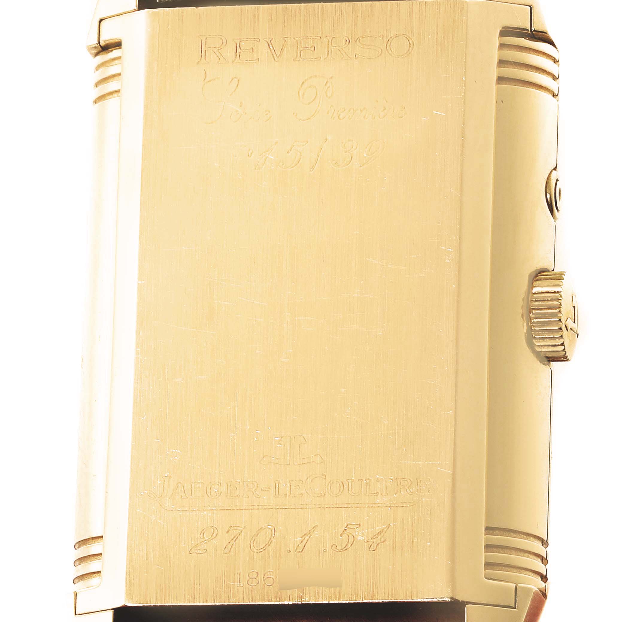 This image shows the back of the Jaeger LeCoultre Reverso 270.1.54 Men's Yellow Gold Red Dial 270.1.54 Men's Yellow Gold Red Dial watch at a slight angle, revealing engravings and the side crown.