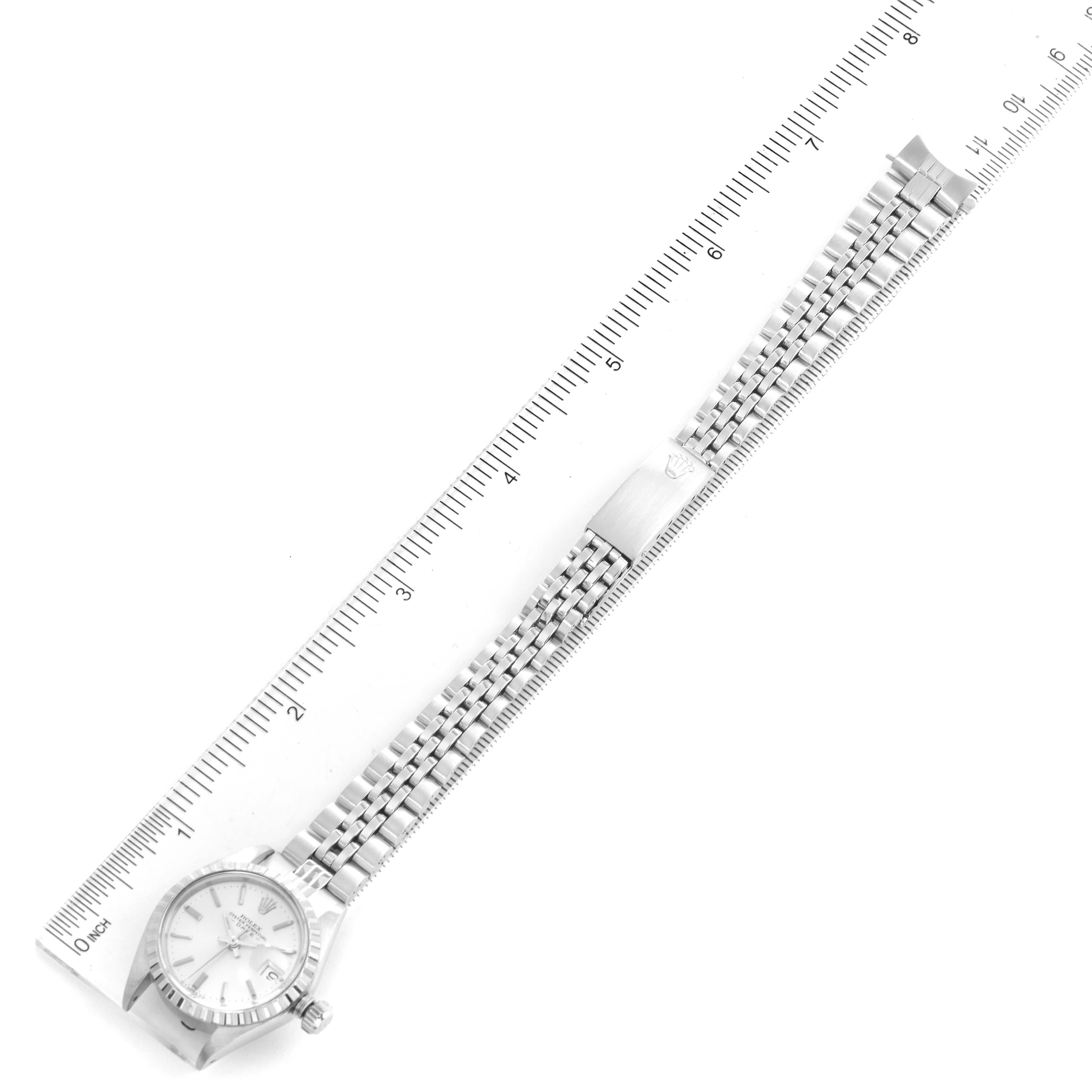 This image shows a Rolex Date 6924 Women
s Stainless Steel Silver Dial 6924 Women
s Stainless Steel Silver Dial model watch laid flat next to a ruler, displaying its entire bracelet and face from a top-down angle.