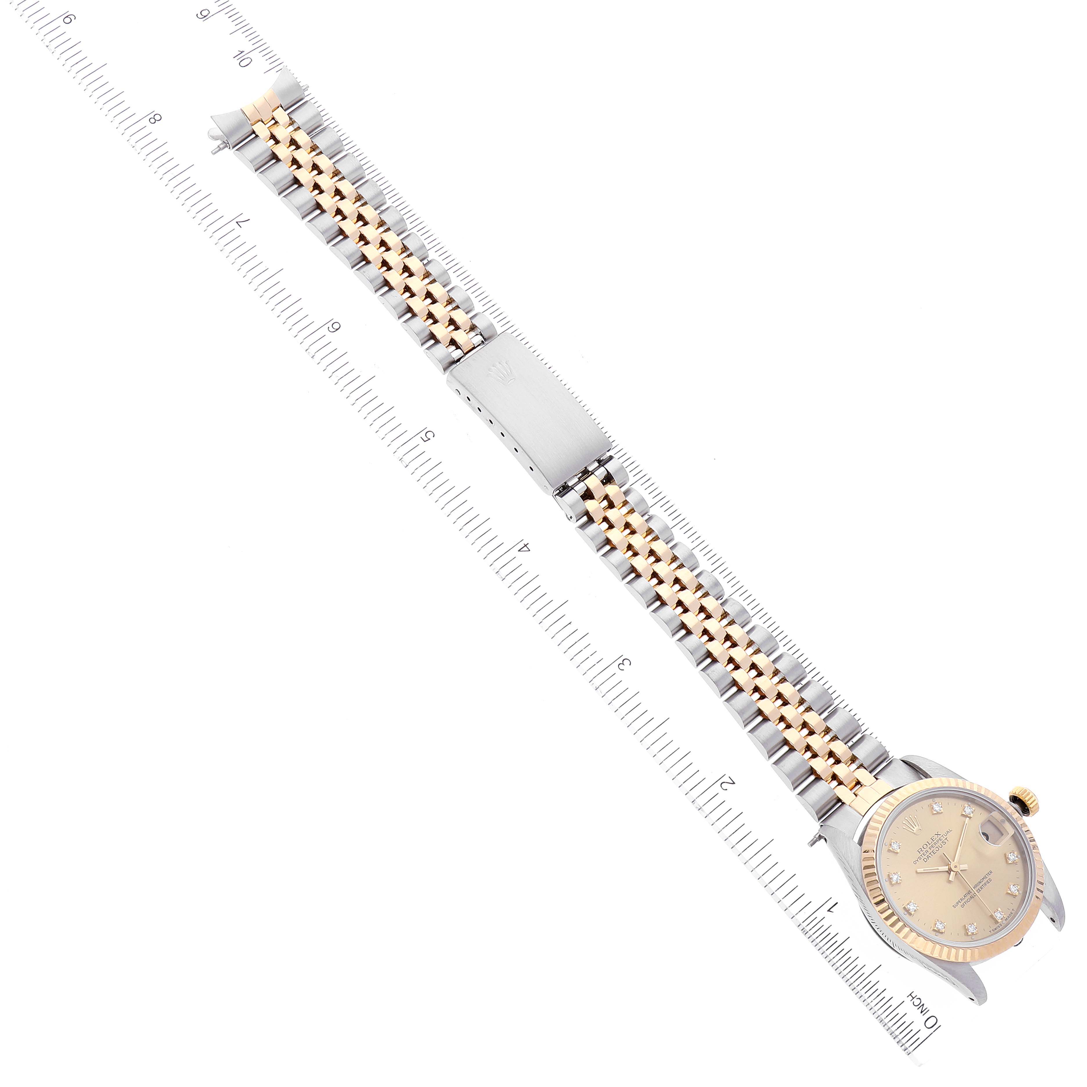 The Rolex Datejust 68273 Women
s Steel and Gold (two tone) Champagne Dial 68273 Women
s Steel and Gold (two tone) Champagne Dial watch is shown from a top-down angle alongside a ruler, displaying its dial, case, and bracelet.