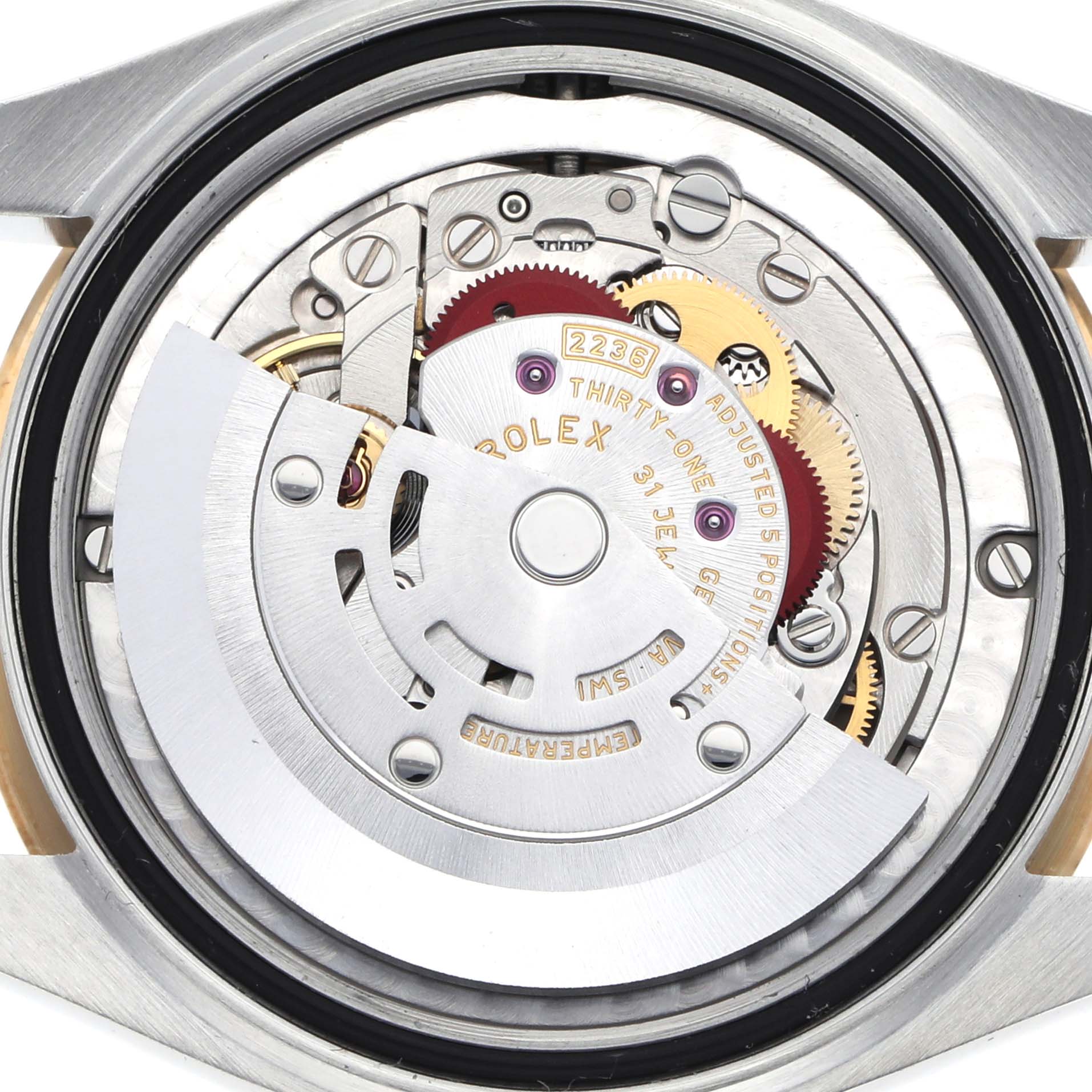 The image shows the movement of a mid-size Rolex watch, focusing on the internal mechanism with gears and the rotor visible.