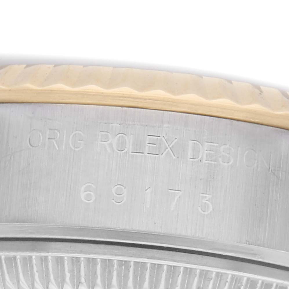 The image shows the side of a Rolex Datejust 69173 Women's Steel and Gold (two tone) White Dial 69173 Women's Steel and Gold (two tone) White Dial watch case with engraved numbers and a partial fluted bezel.