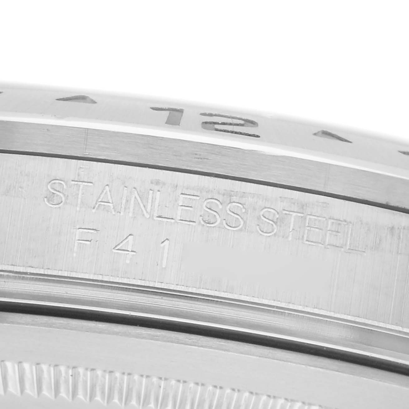 The image shows a close-up side angle of the Rolex Explorer 16570 Men
s Stainless Steel White Dial 16570 Men
s Stainless Steel White Dial
s stainless steel bezel, featuring engraved text.