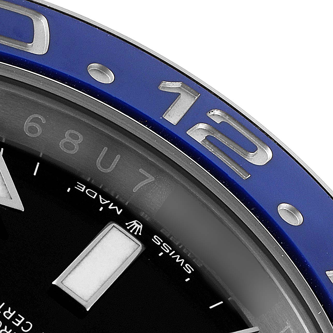 This close-up image of a Rolex GMT-Master 126710 Men
s Stainless Steel Black Dial 126710 Men
s Stainless Steel Black Dial watch shows part of the bezel, the 12-hour marker, and part of the dial indicating "Swiss Made."