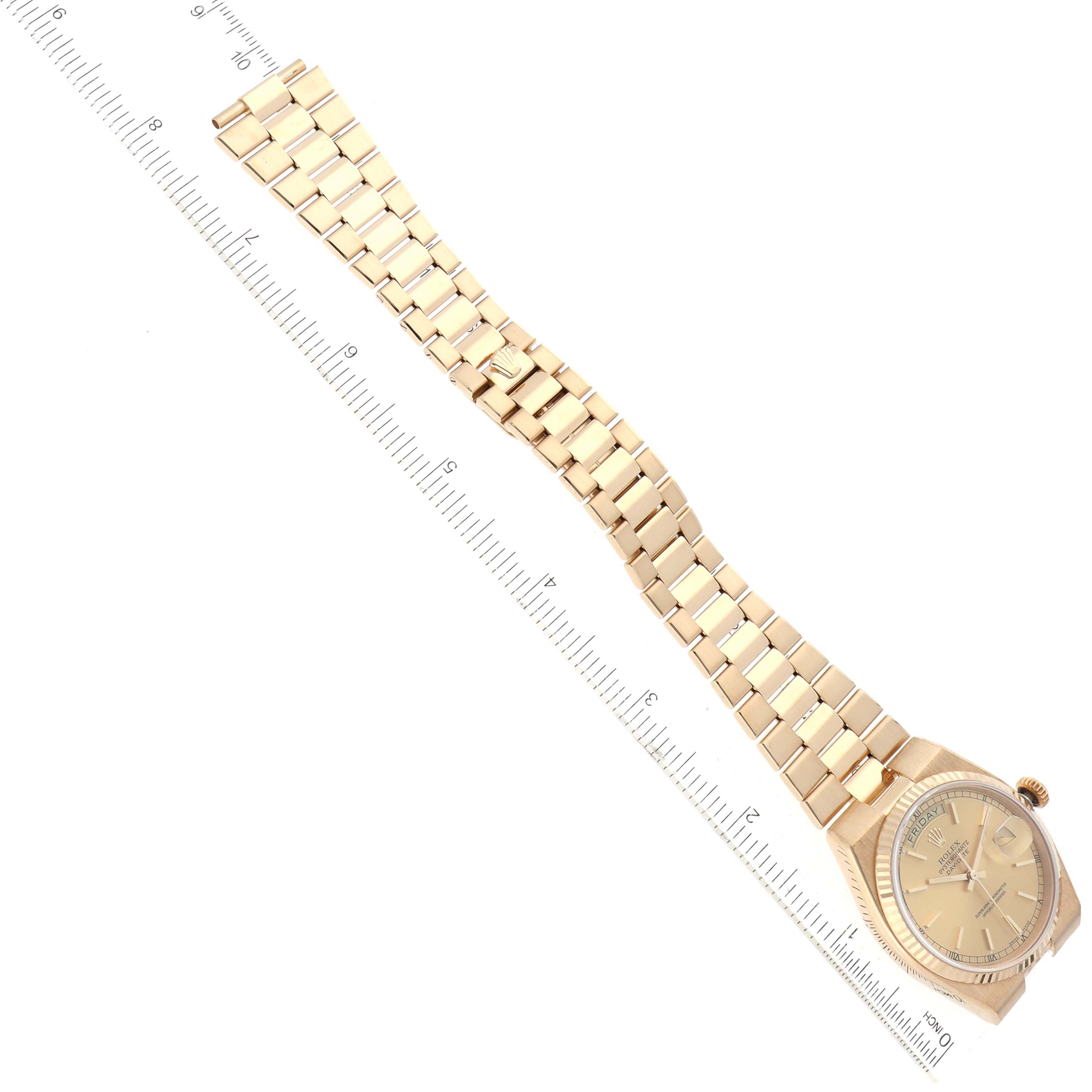 The Rolex Oysterquartz 19018 Men's Yellow Gold Champagne Dial 19018 Men's Yellow Gold Champagne Dial watch is shown from a top-down angle, fully extended with its bracelet and face visible, alongside a ruler for scale.