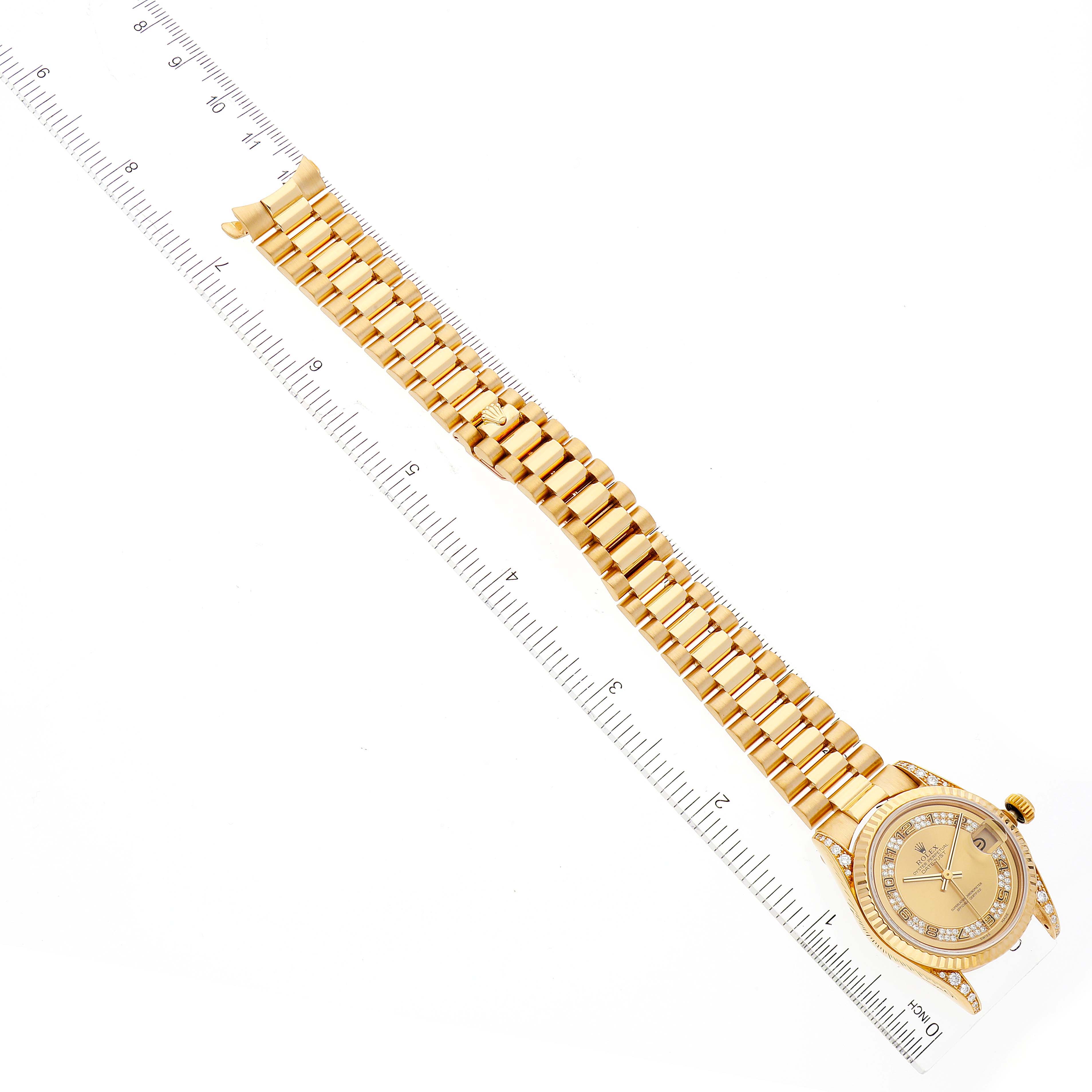 The Rolex President 68238 Women's Yellow Gold Champagne Dial 68238 Women's Yellow Gold Champagne Dial model watch is shown from a top-down angle, highlighting its gold bracelet and face aligned with a ruler.
