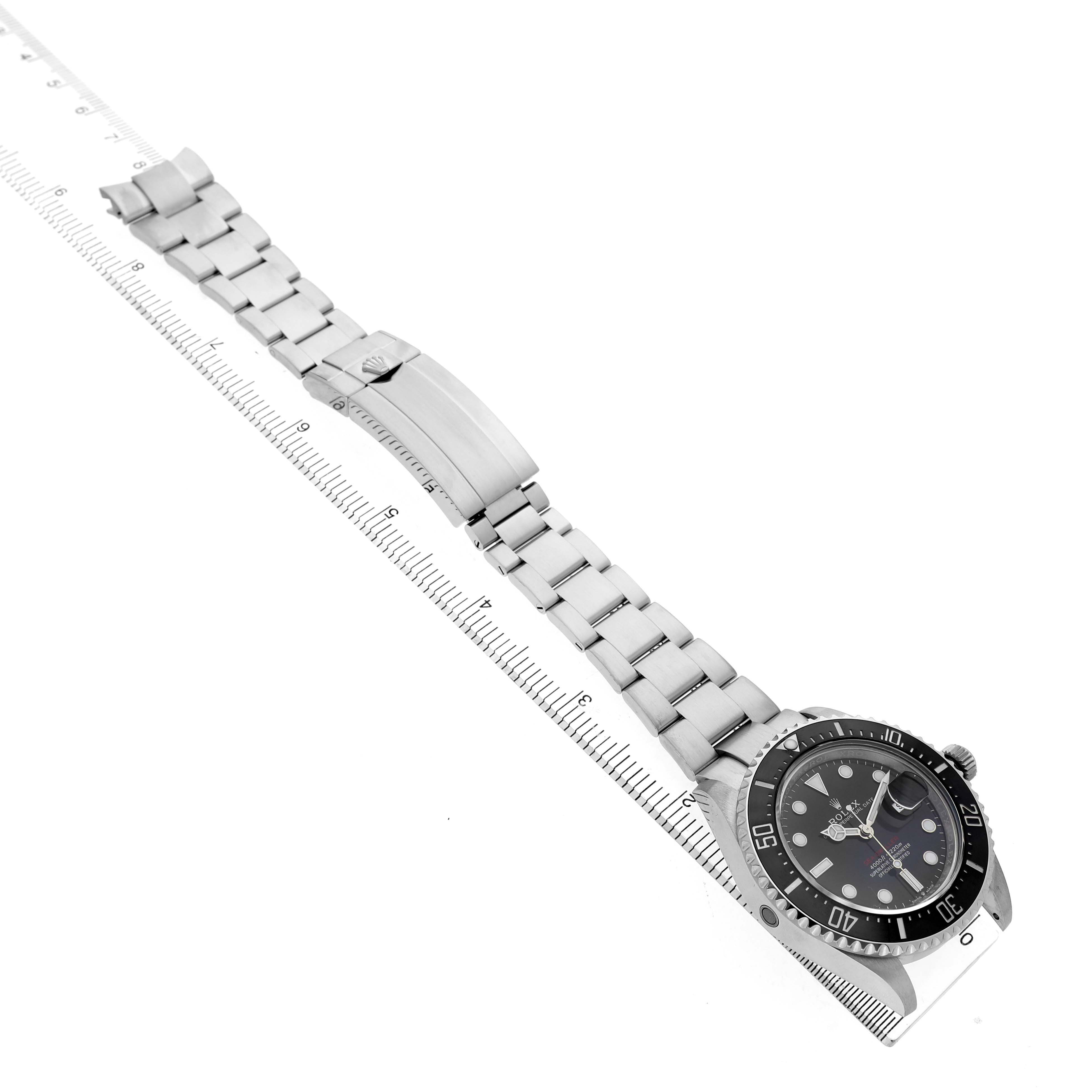 The Rolex Sea-Dweller 126600 Men's Stainless Steel Black Dial is shown at a diagonal angle, displaying the full bracelet and clasp alongside a measuring ruler.