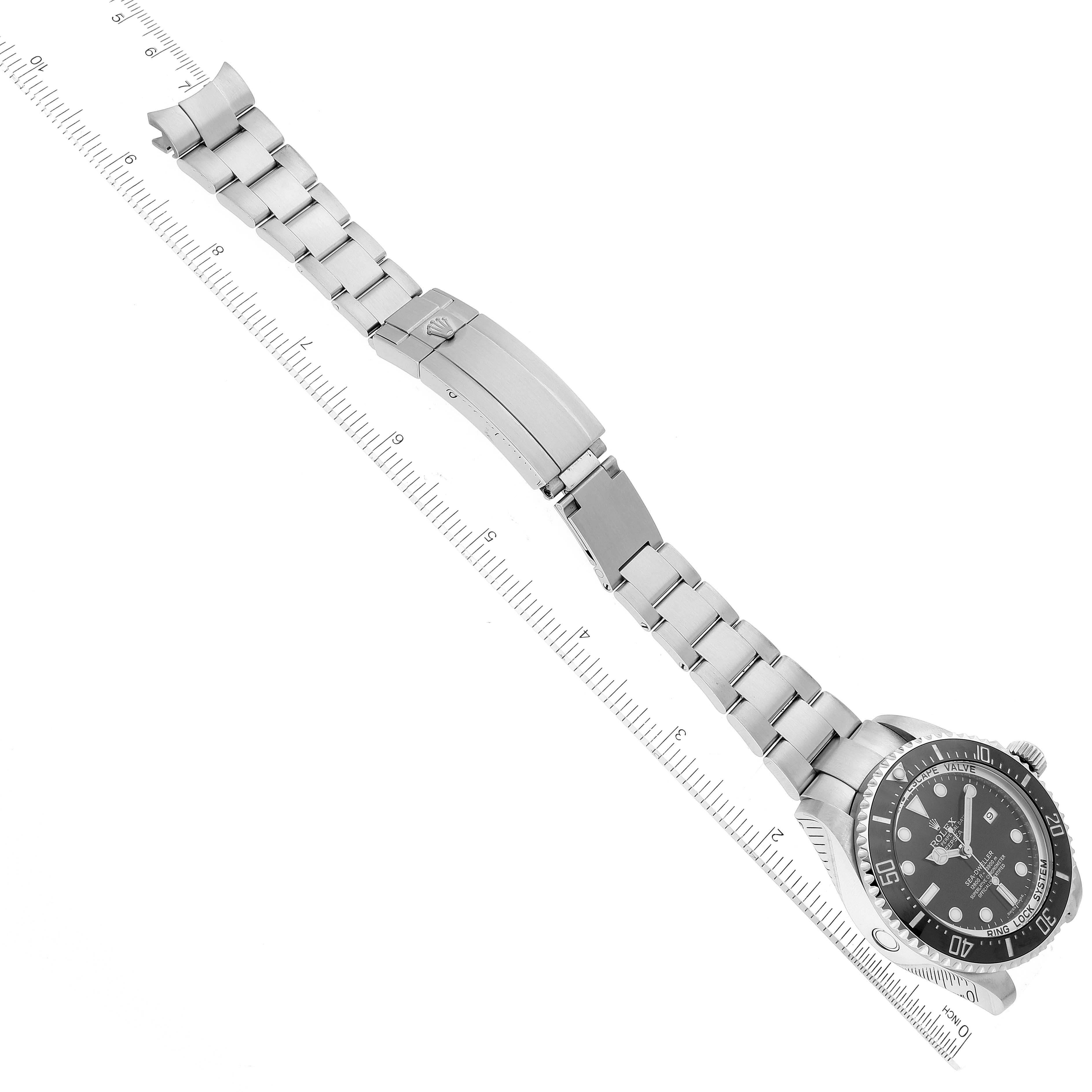 The Rolex Sea-Dweller 116660 Men's Stainless Steel Black Dial 116660 Men's Stainless Steel Black Dial watch is shown at an angle displaying the face, bezel, bracelet, and clasp, with a ruler for measurement.