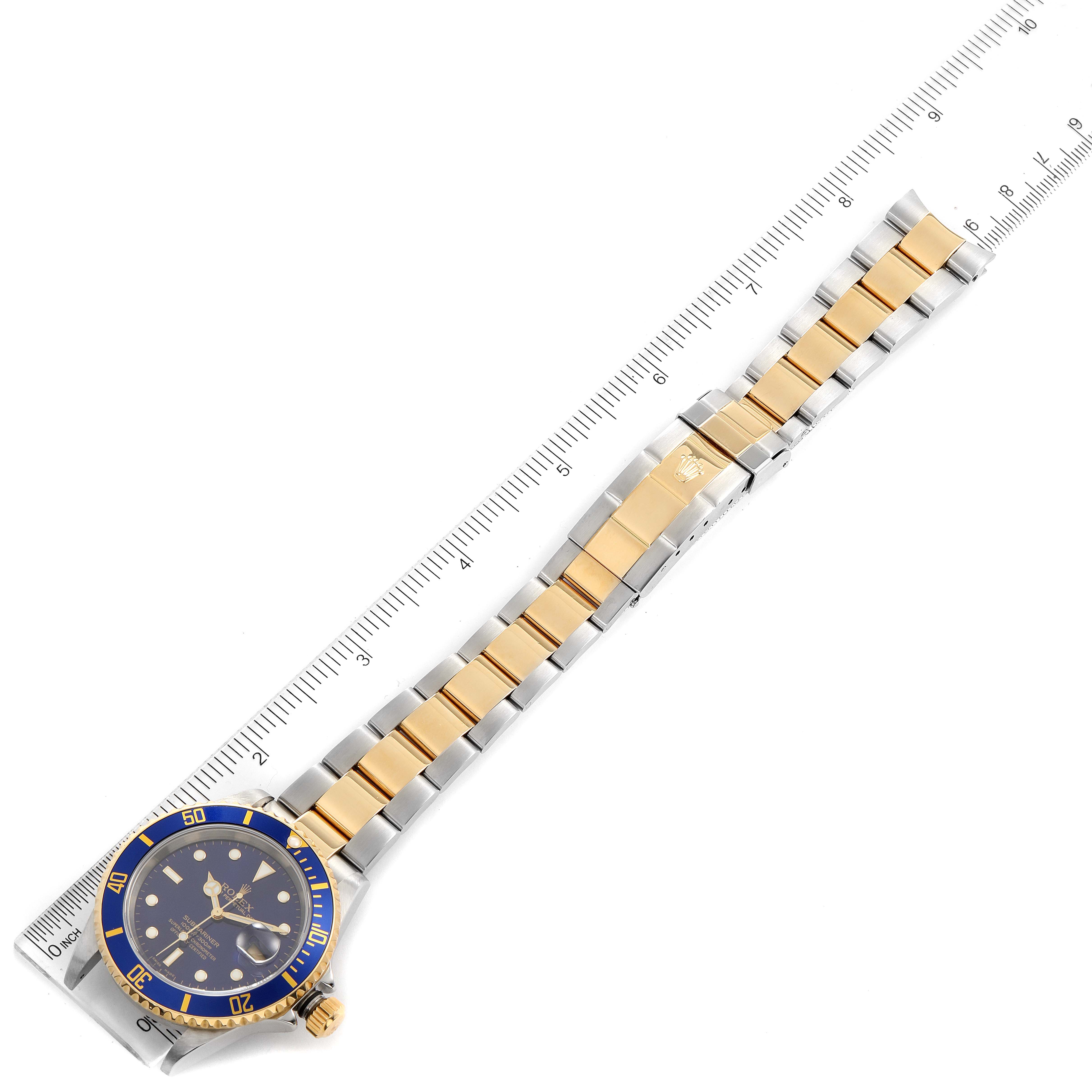 The image shows a top-down view of a Rolex Submariner 16613 Men
s Steel and Gold (two tone) Blue Dial 16613 Men
s Steel and Gold (two tone) Blue Dial watch with its full bracelet and a ruler for scale.