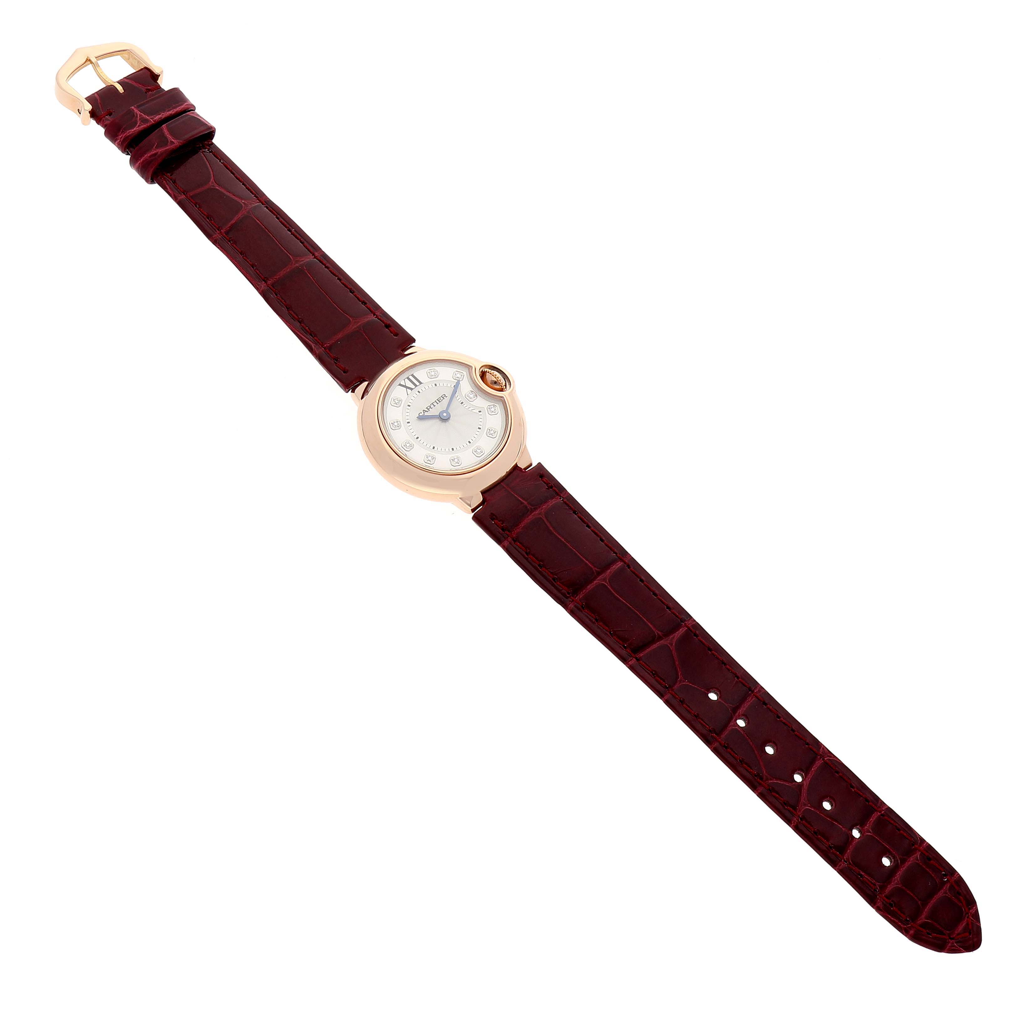 The image displays a Cartier Ballon Bleu WE902050 Women
s Rose Gold Silver Dial WE902050 Women
s Rose Gold Silver Dial watch from a top-down angle, showing the full watch and its burgundy leather strap.