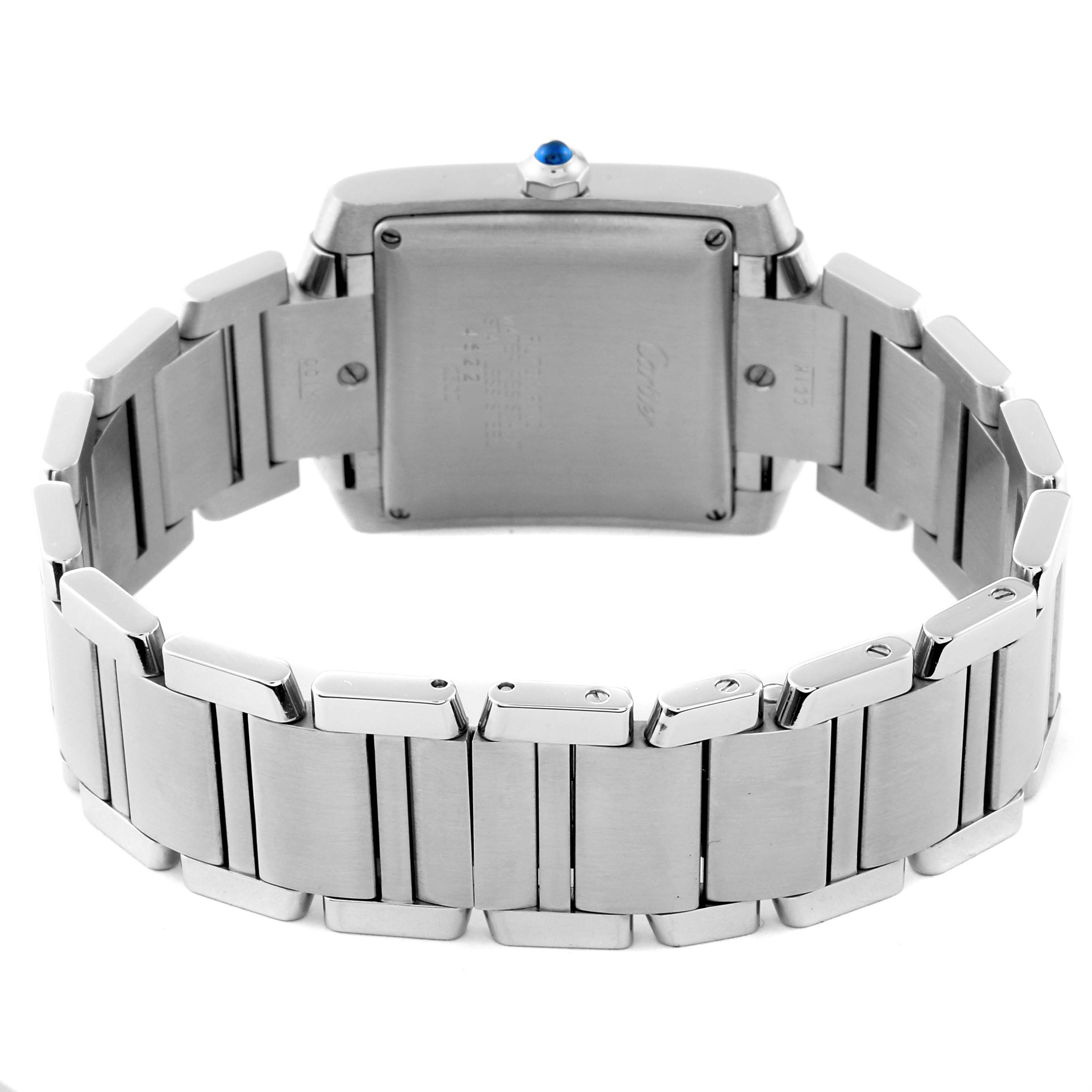 The image shows the back and bracelet of a Cartier Tank Française watch, showcasing its stainless steel case and blue cabochon crown.