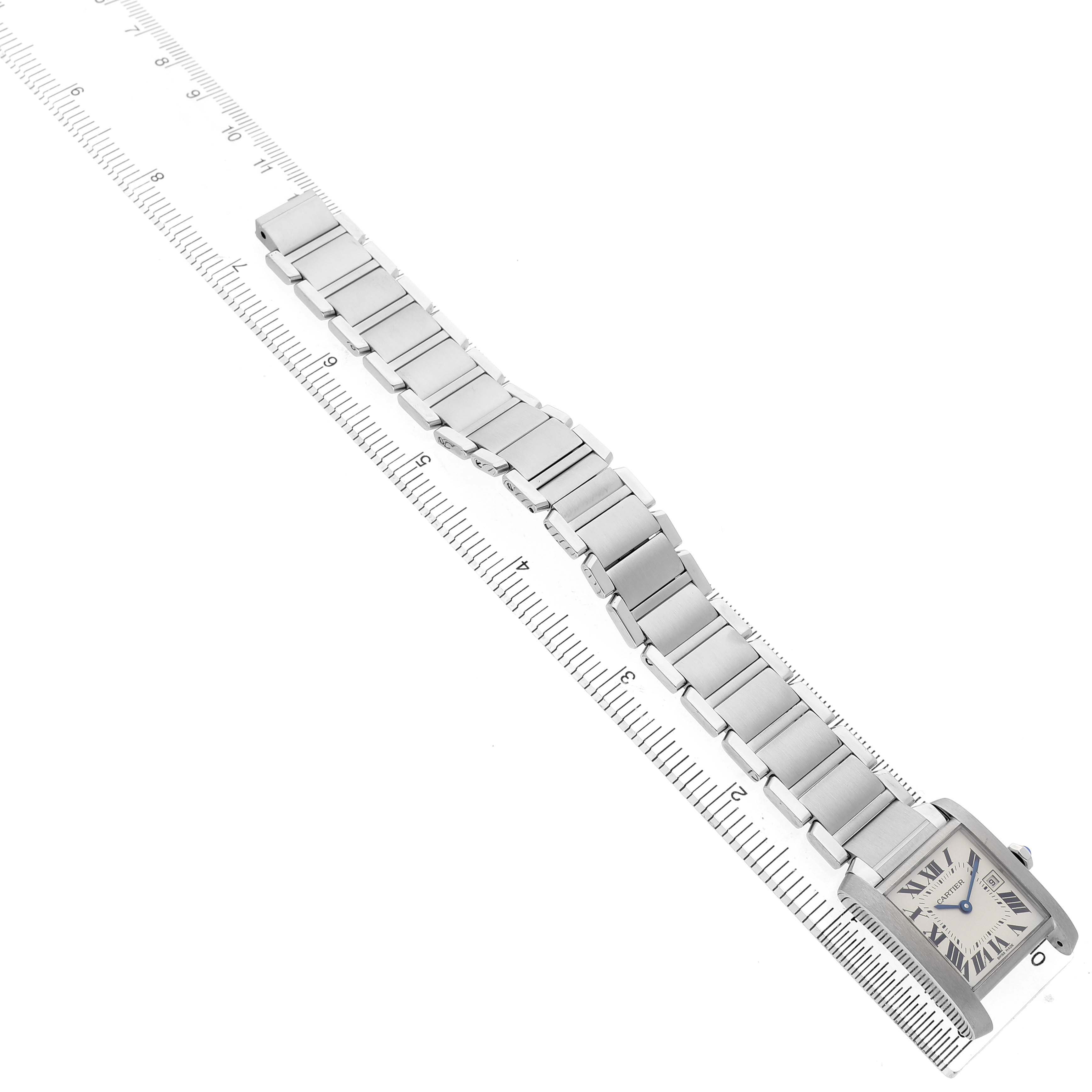The Cartier Tank Française watch is shown from a top angle with its bracelet extended alongside a ruler.