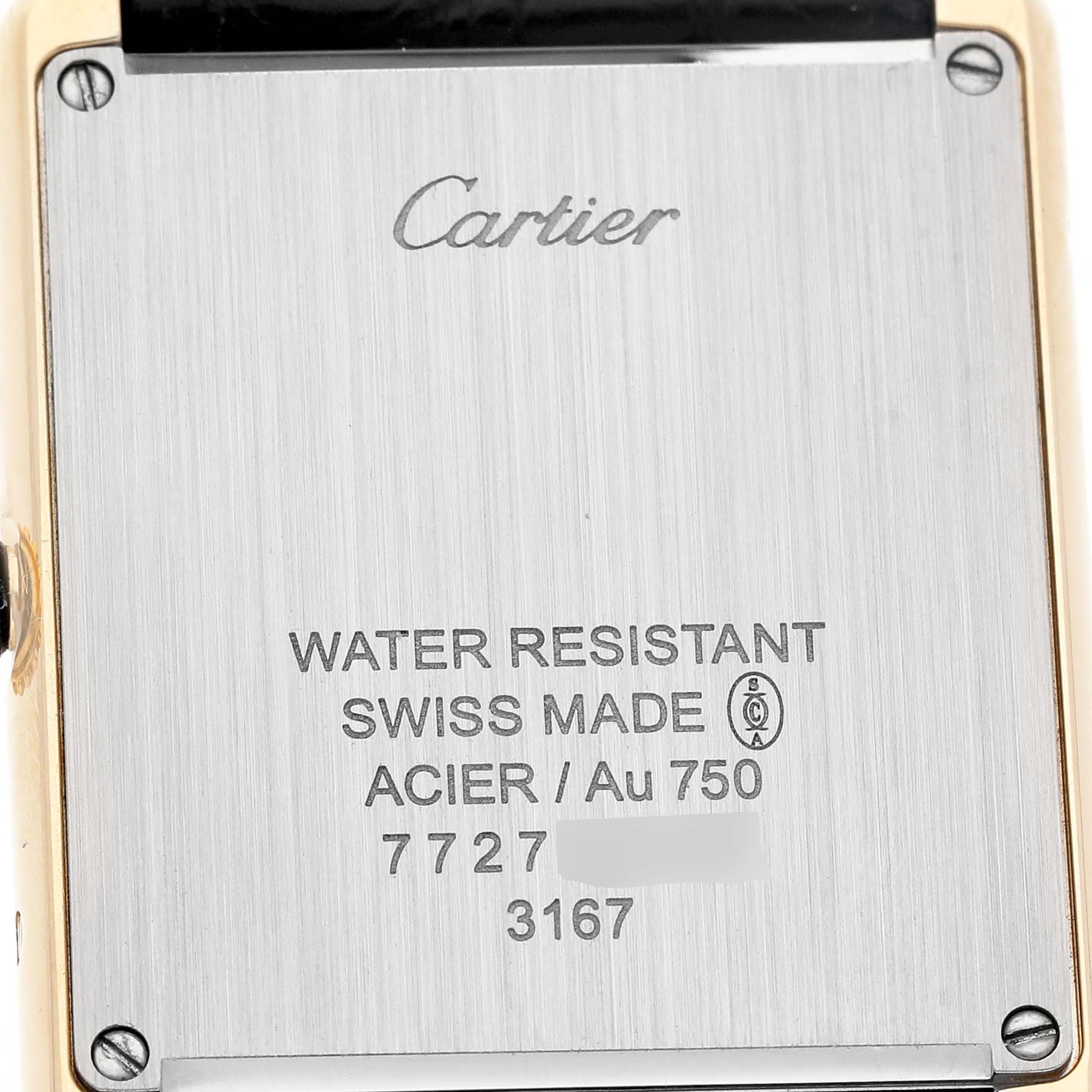 The image shows the back case of a Cartier Tank Solo W5200004 Men's Yellow Gold Silver Dial watch, featuring engraving details and screws.