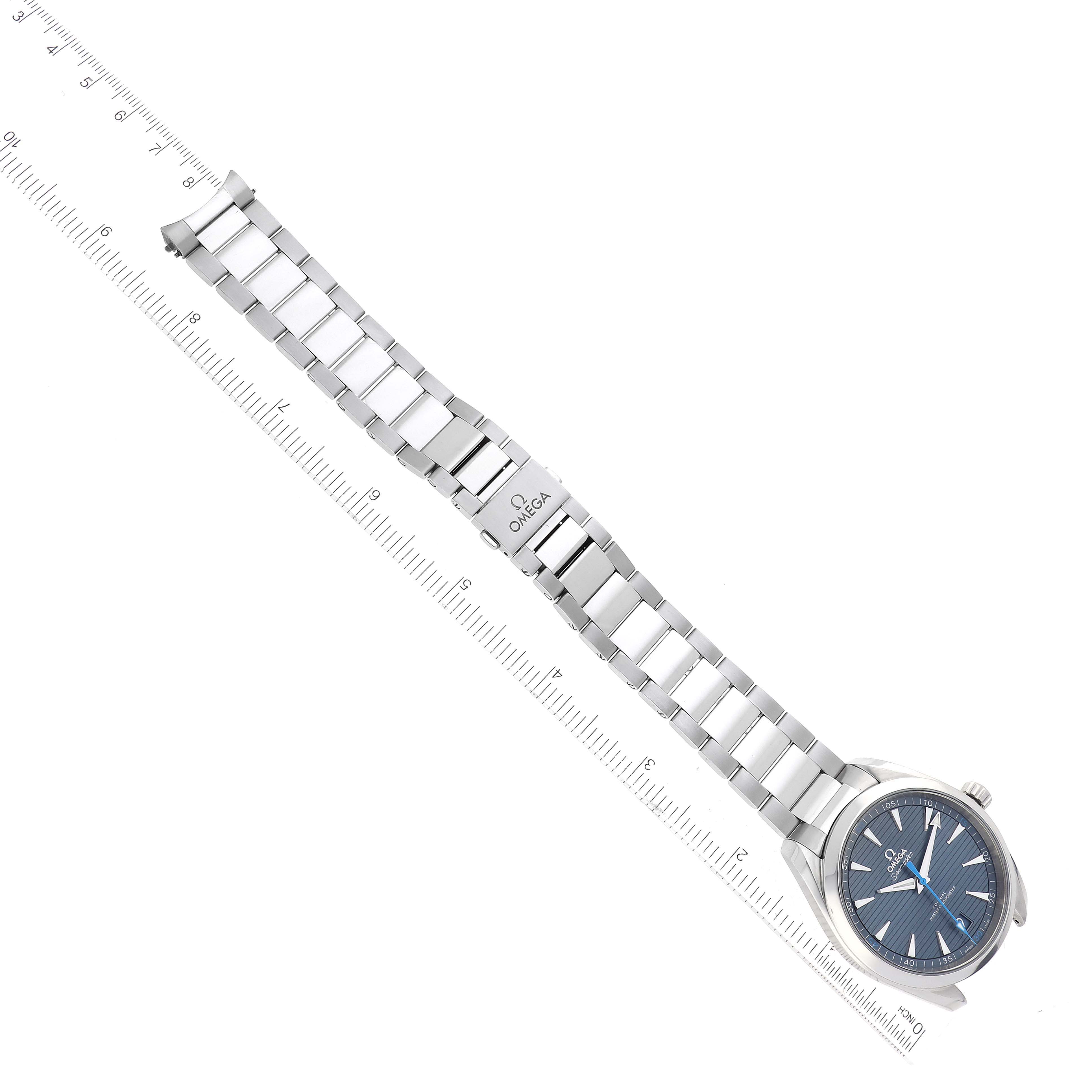 The image shows an Omega Aqua Terra 220.10.41.21.03.002 Men
s Stainless Steel Blue Dial 220.10.41.21.03.002 Men
s Stainless Steel Blue Dial watch and metal bracelet positioned at an angle over a measurement ruler.